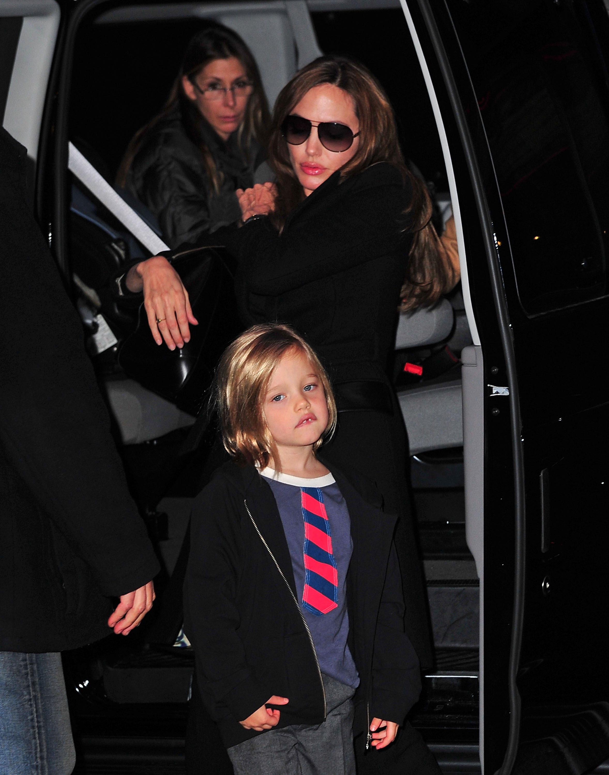 Shiloh Jolie-Pitt steps out in New York City wearing a jacket and tie, embracing a sharp, boyish look. Beside her, Angelina Jolie follows closely in sleek black and sunglasses. The outing highlights Shiloh’s growing confidence in her distinctive style.