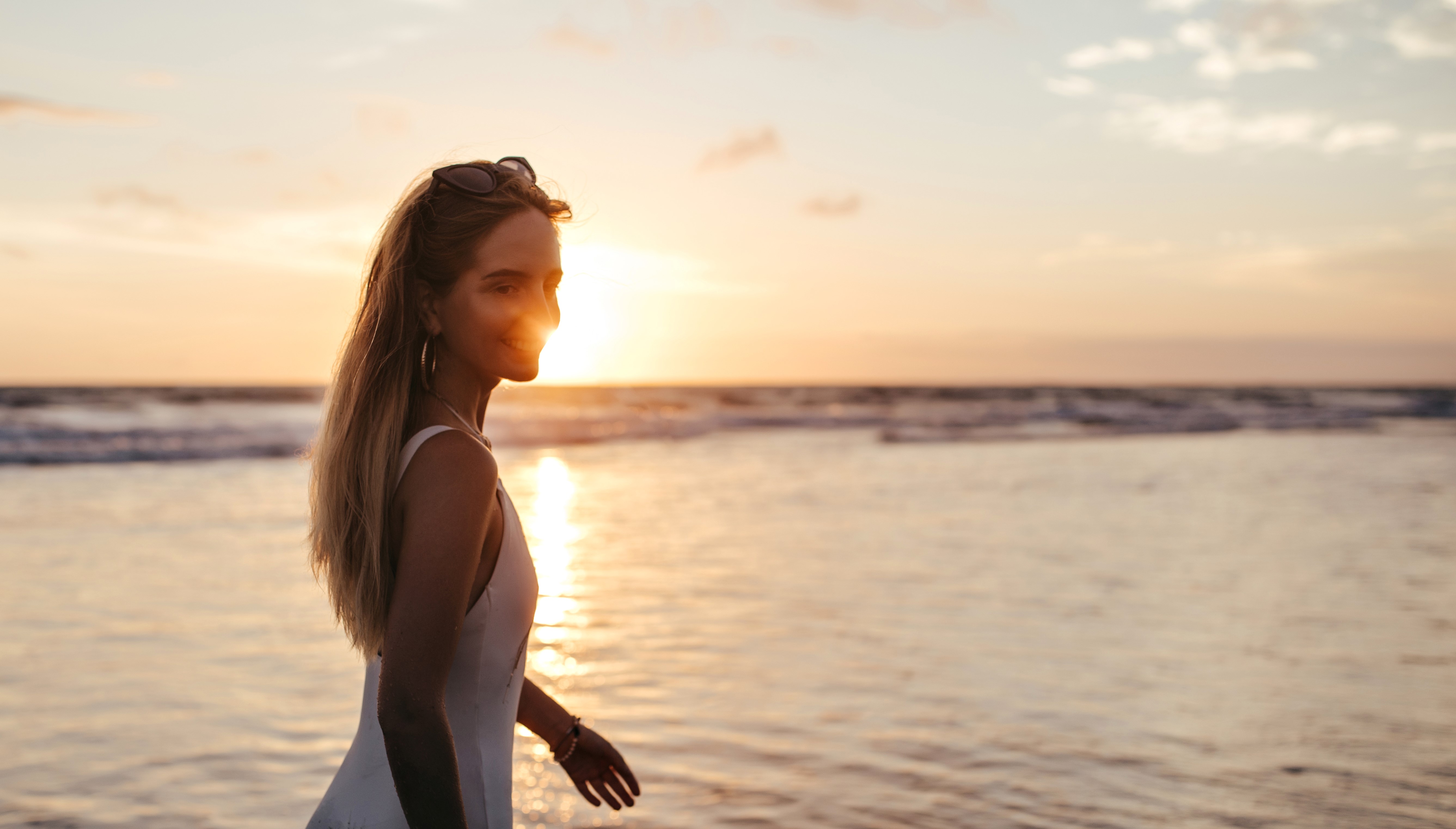 A smiling woman in a white swimsuit near the sea | Source: Freepik