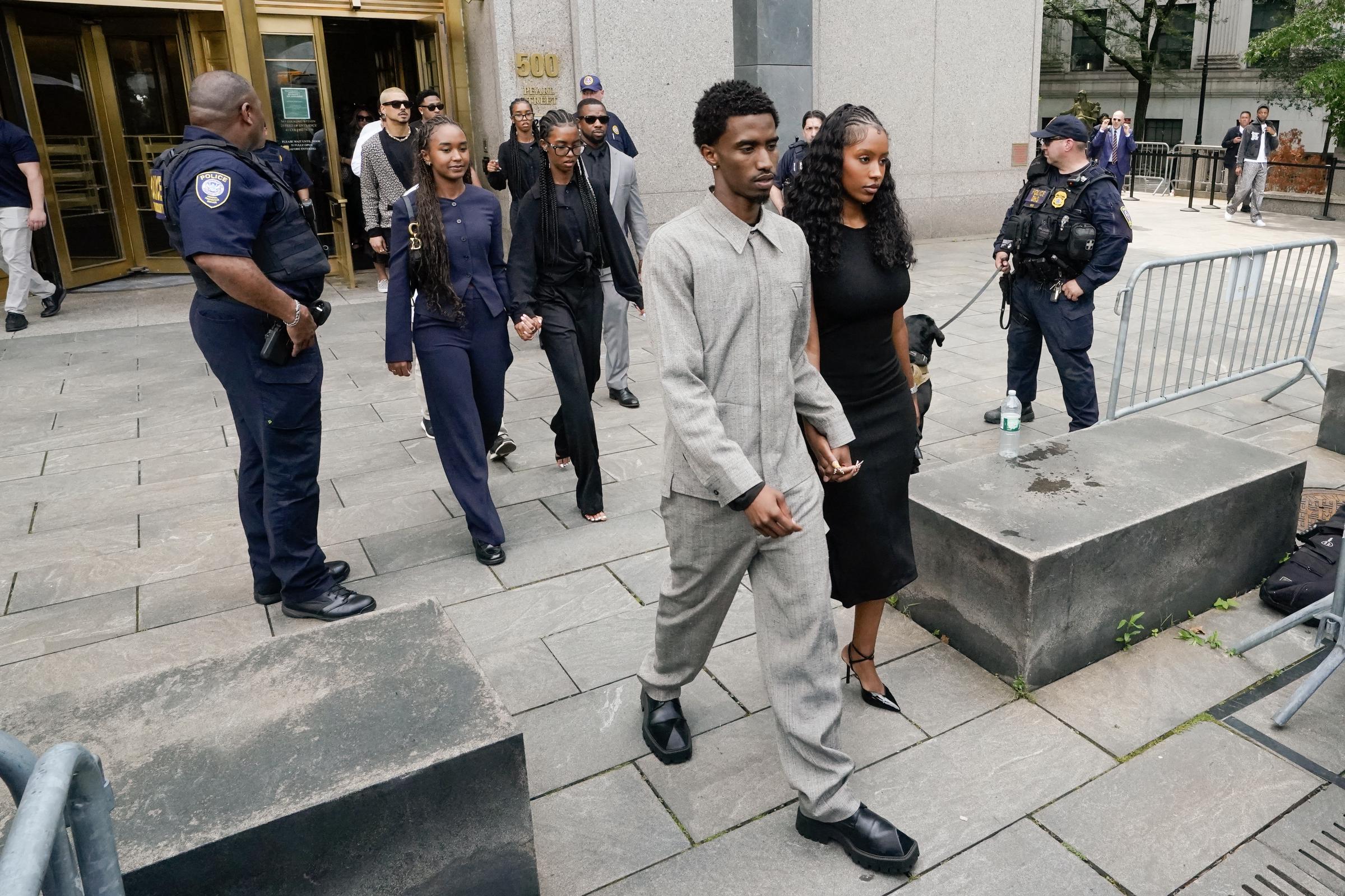 King Combs walks ahead, leading family members away from the courthouse. The group moves calmly, holding hands, with few expressions revealing emotion.
