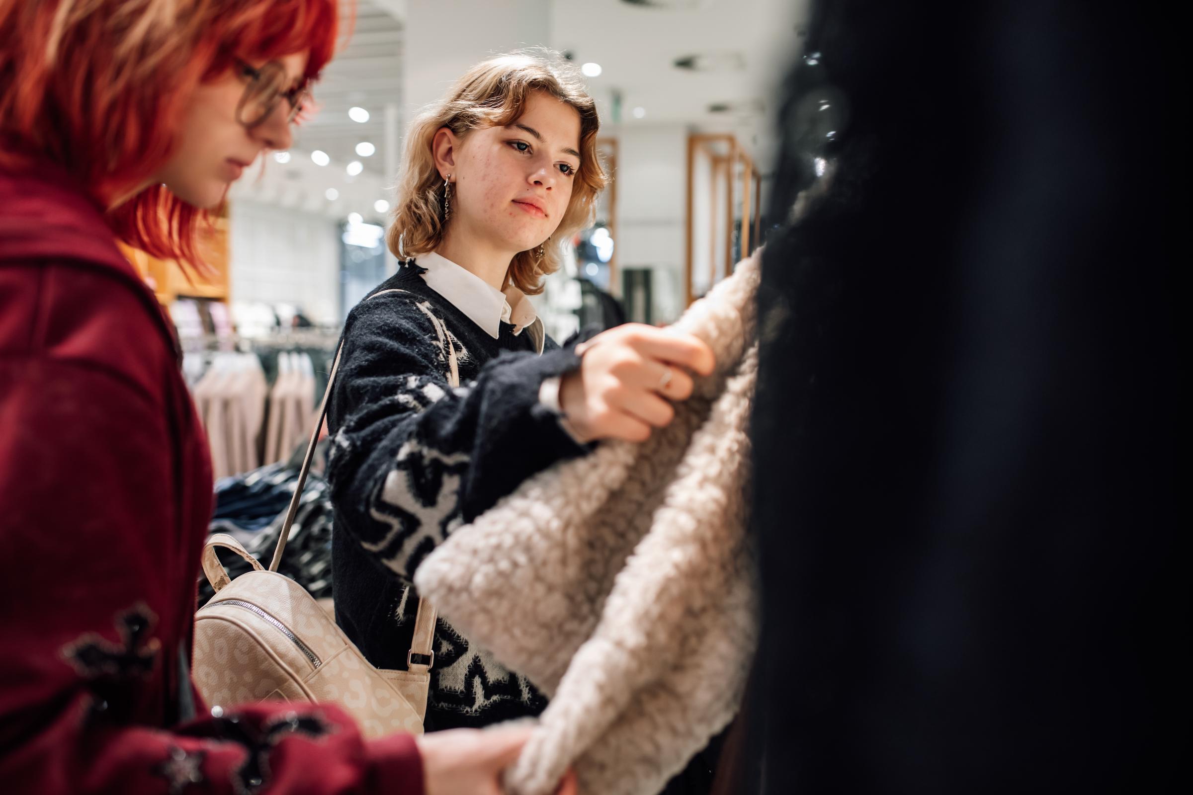 Two young women browsing a clothing rack | Source: Getty Images
