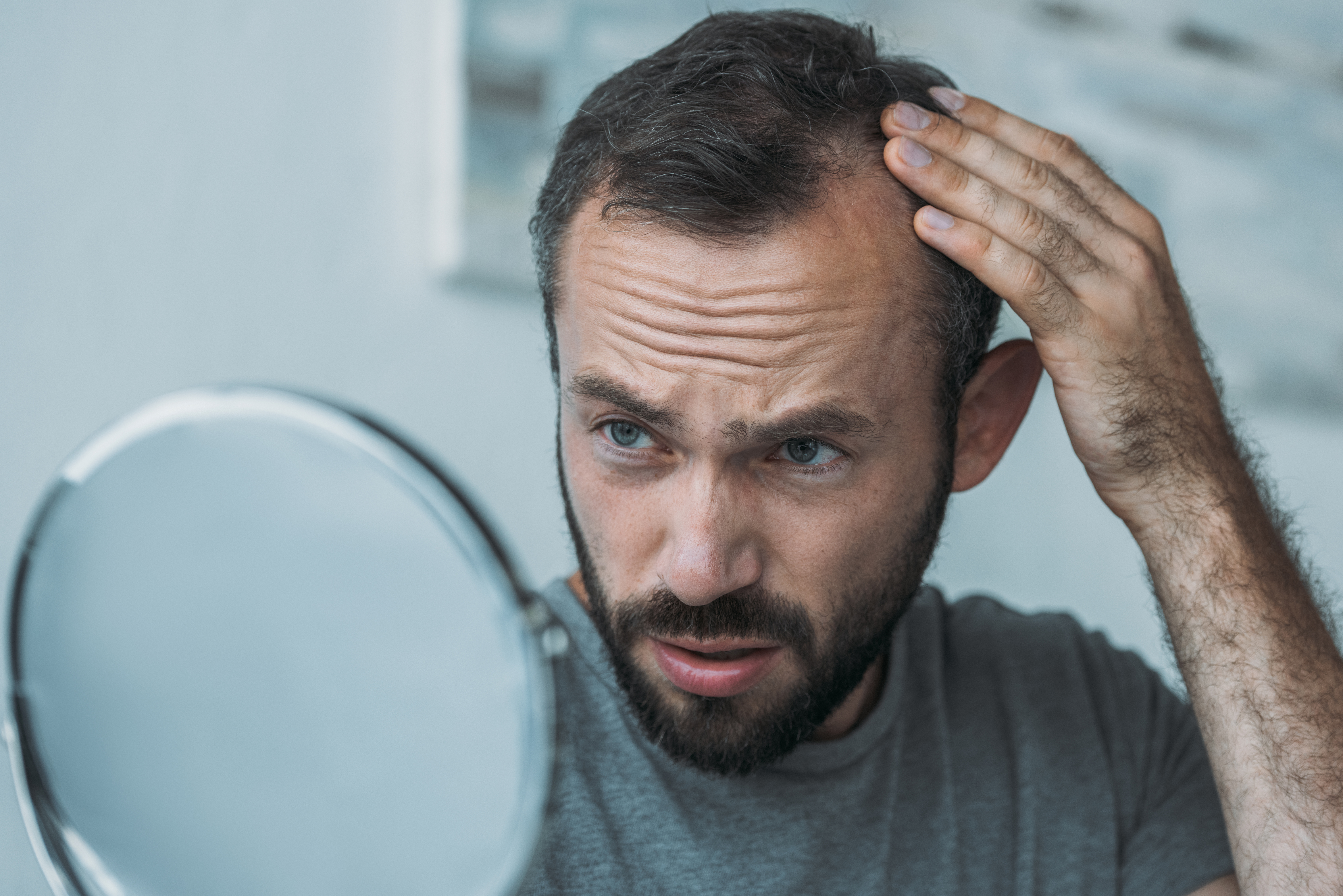 A man looking out for bald spots in the mirror | Source: Getty Images