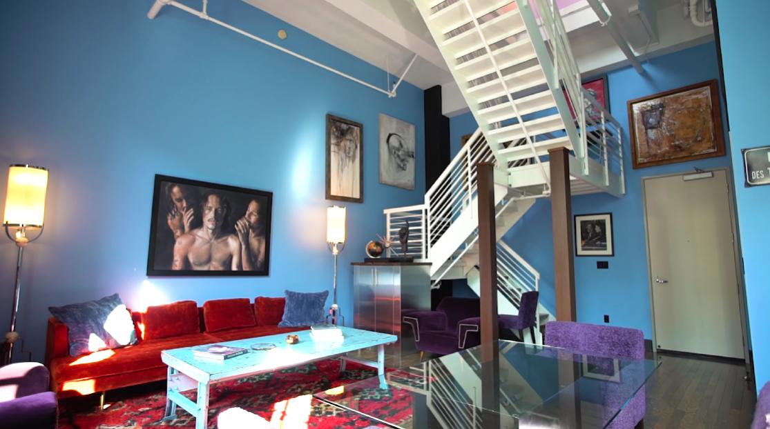 Johnny Depp and Amber's bright blue lounge area with portraits hung up on the wall and a white staircase. / Source: YouTube@ThePropertyCountdown