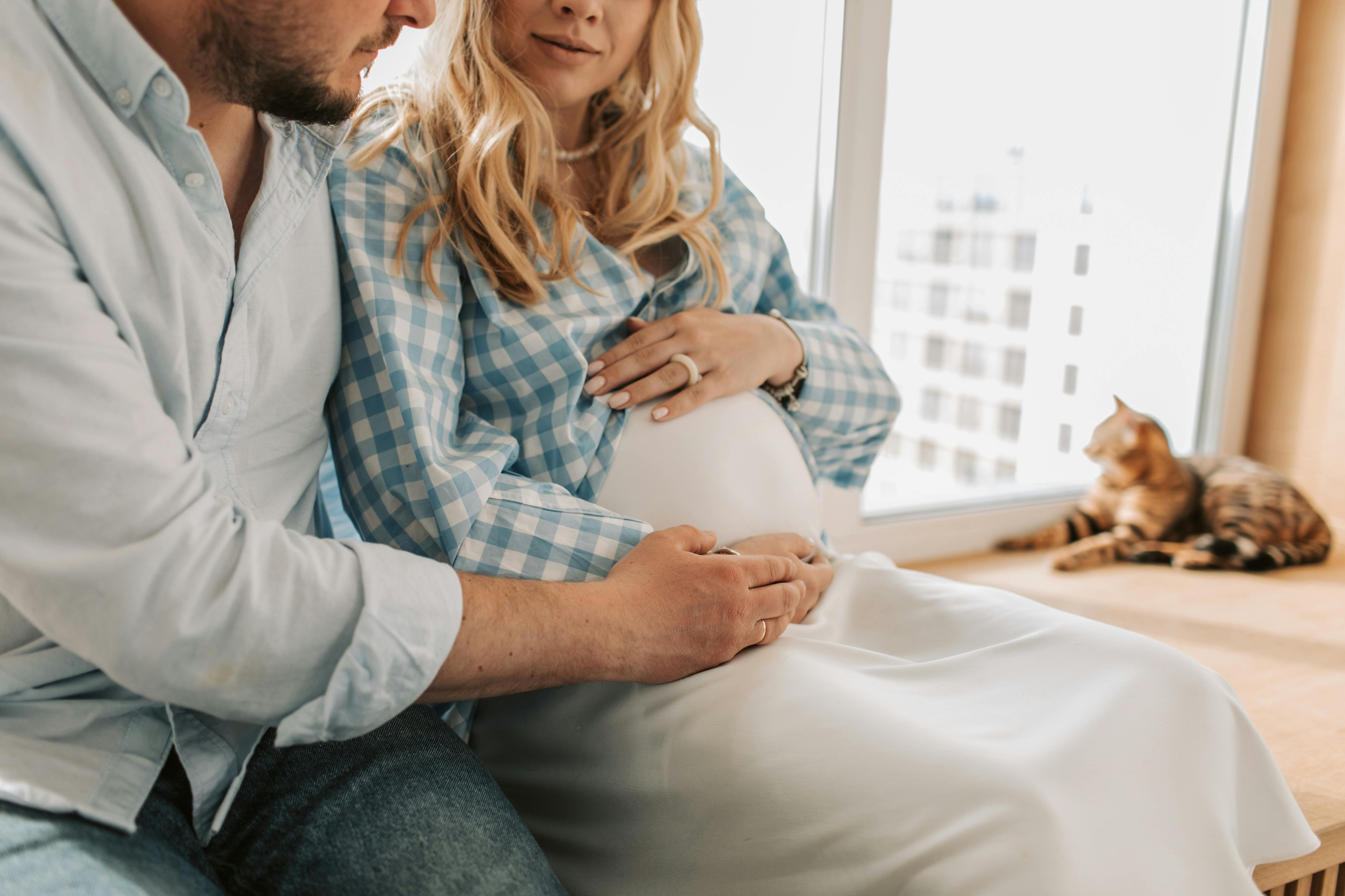 A pregnant woman and a man side-by-side on a sofa | Source: Pexels