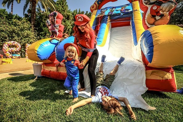 Christina Aguilera (C), her daughter Summer Rain Rutler (L) and son Max Liron Bratman smile and laugh as they slide down the play slide during the second birthday party for Christina Aguilera's daughter Summer Rain Rutler at a private residence on August 20, 2016, in Beverly Hills, California. | Source: Getty Images.