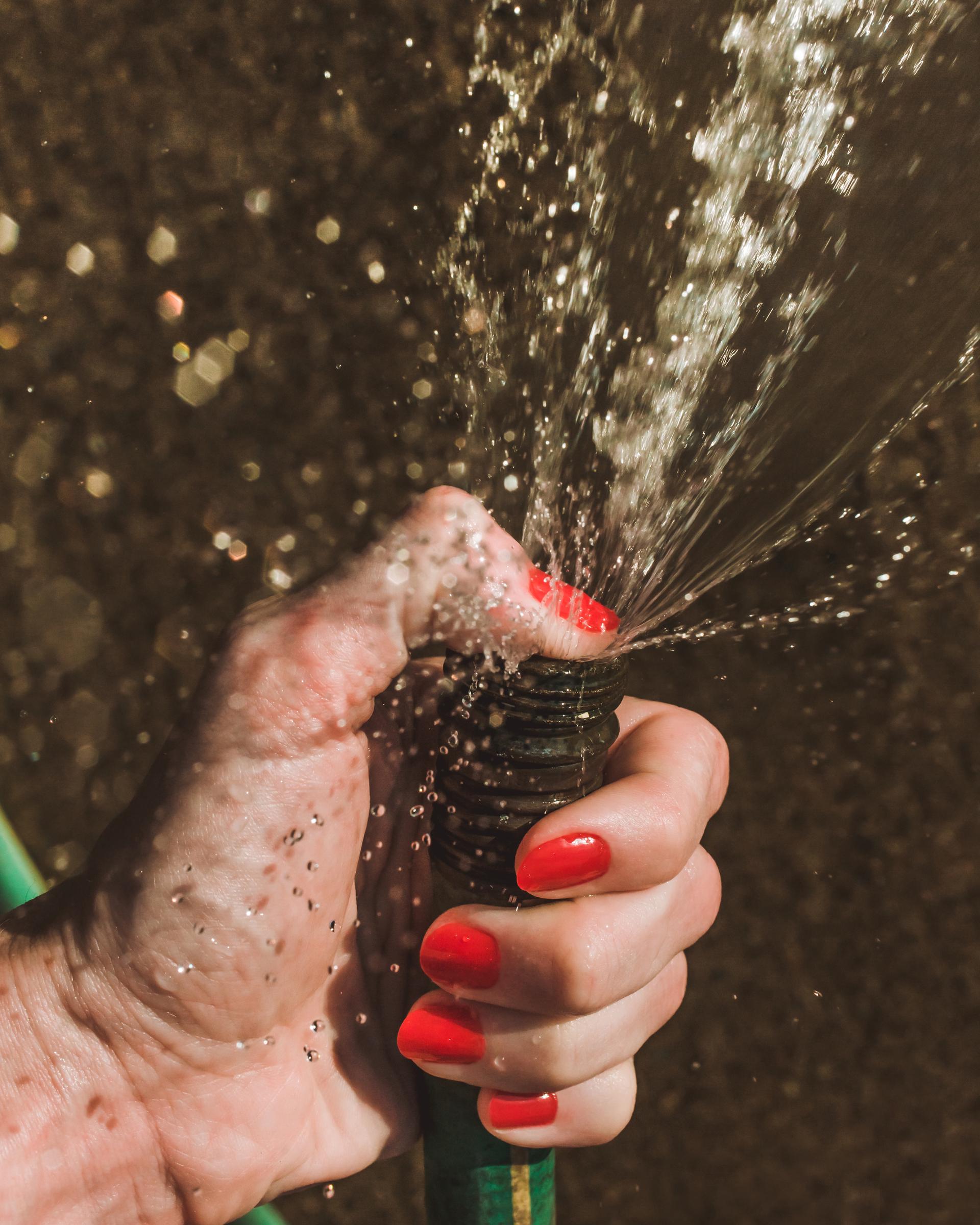 A close-up of a woman's hand holding a hose | Source: Getty Images