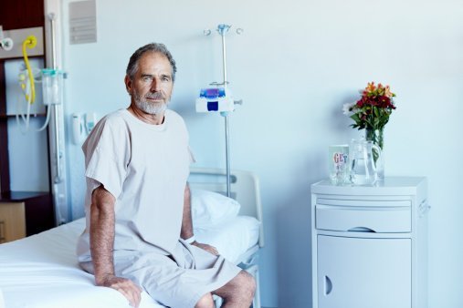 A mature man sitting on bed in hospital ward | Photo: Getty Images 