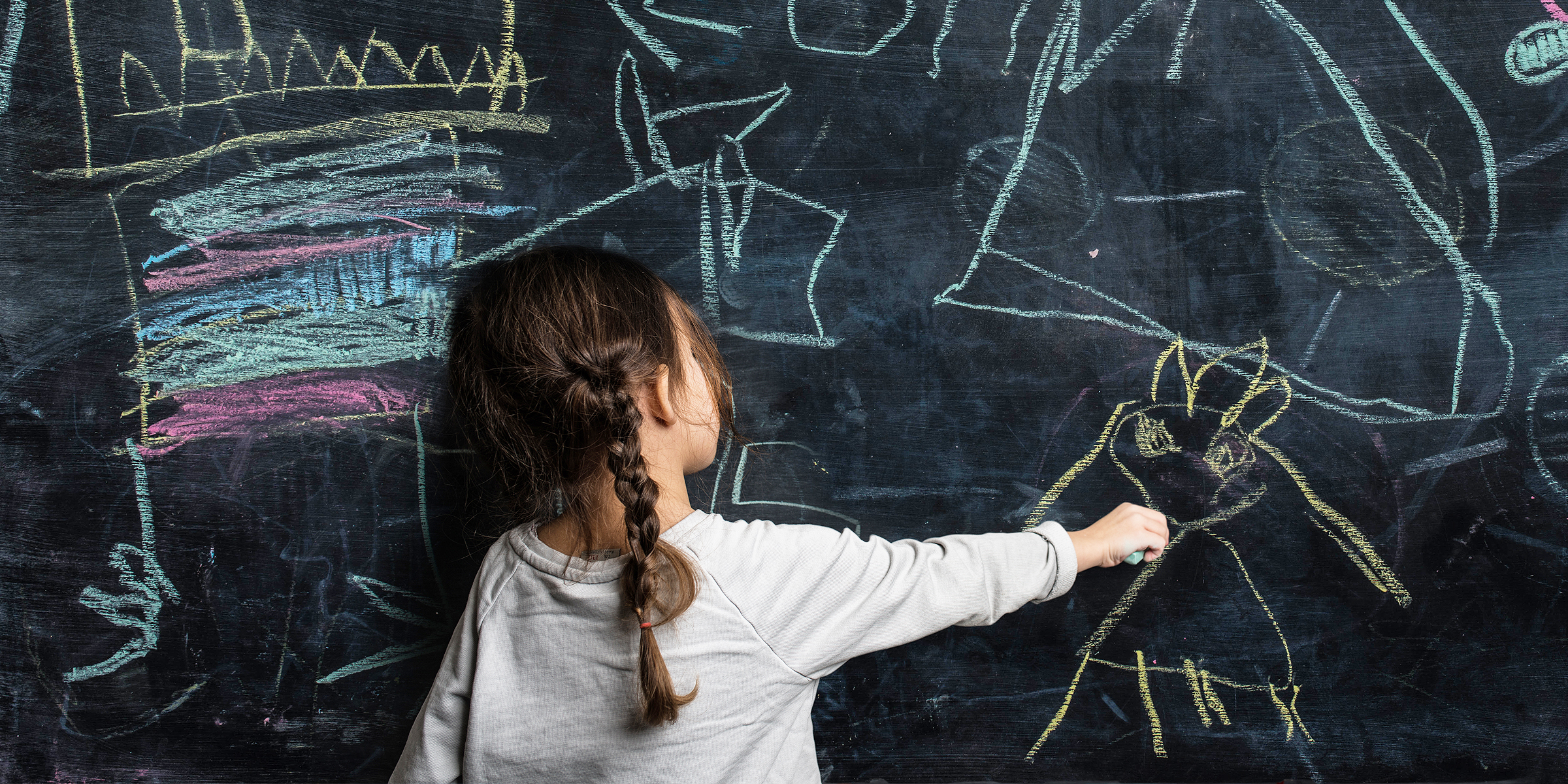 Little girl writing on a chalk board | Source: Getty Images