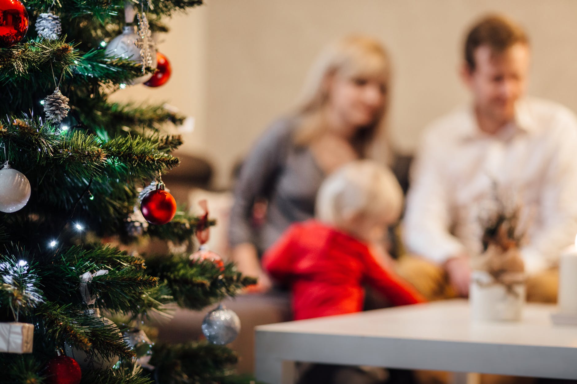 A blurred photo of a family at their Christmas tree. | Photo: Pexels