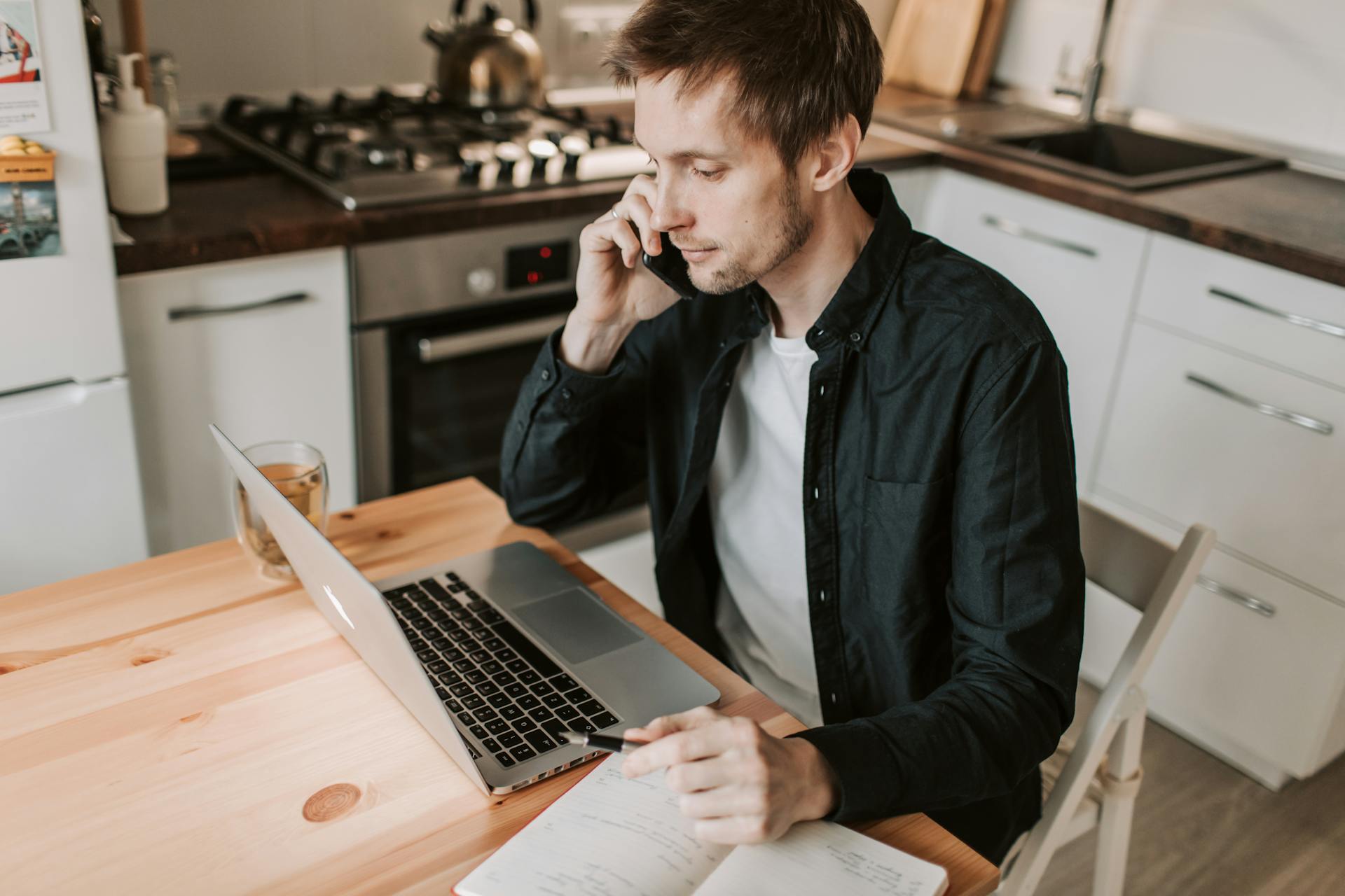 Mean seated at a kitchen table making a phone call | Source: Pexels