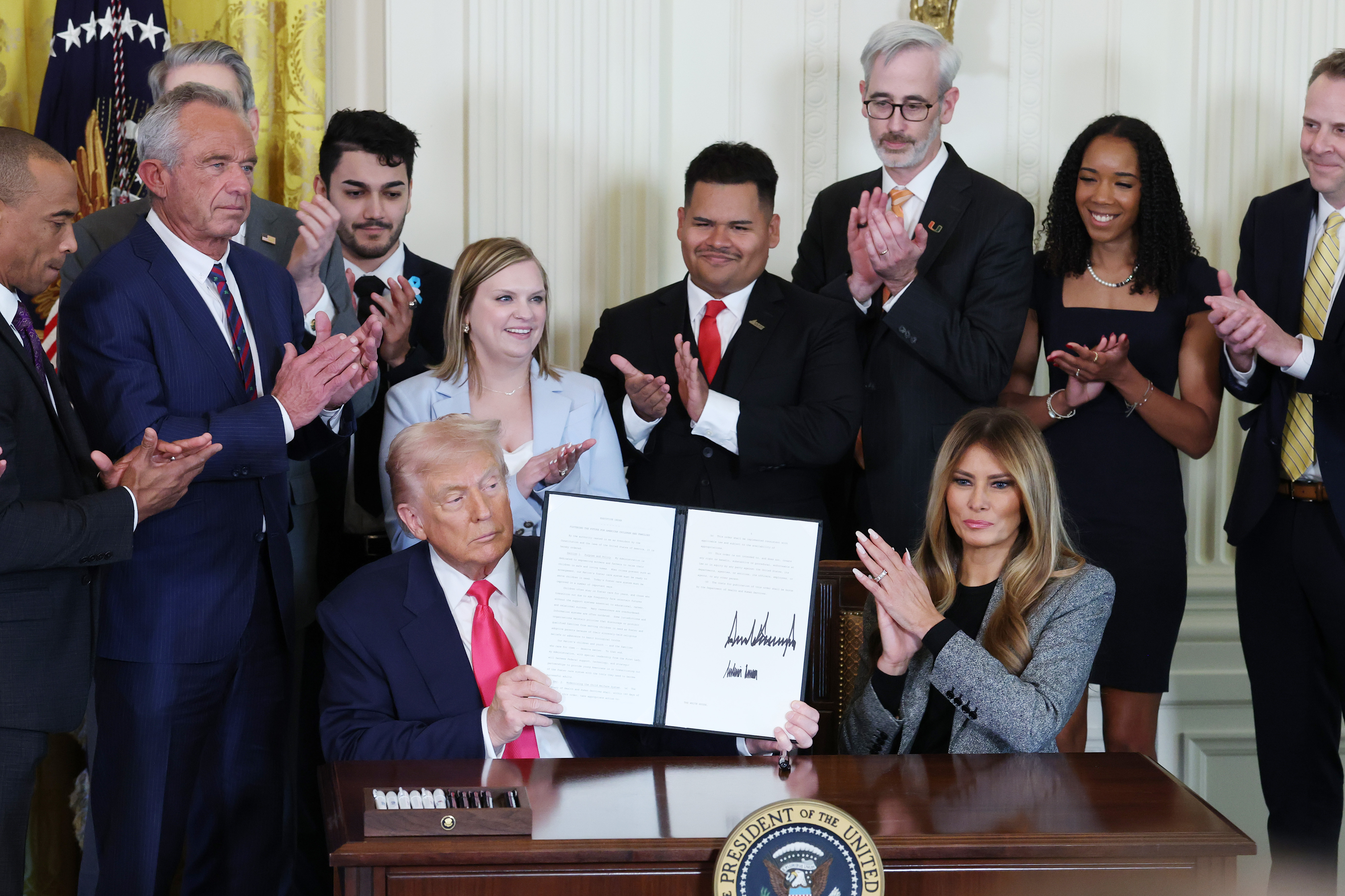 Donald Trump joined by Melania Trump and members of his administration and foster care advocates, signs the "Fostering the Future" executive order on November 13, 2025 | Source: Getty Images