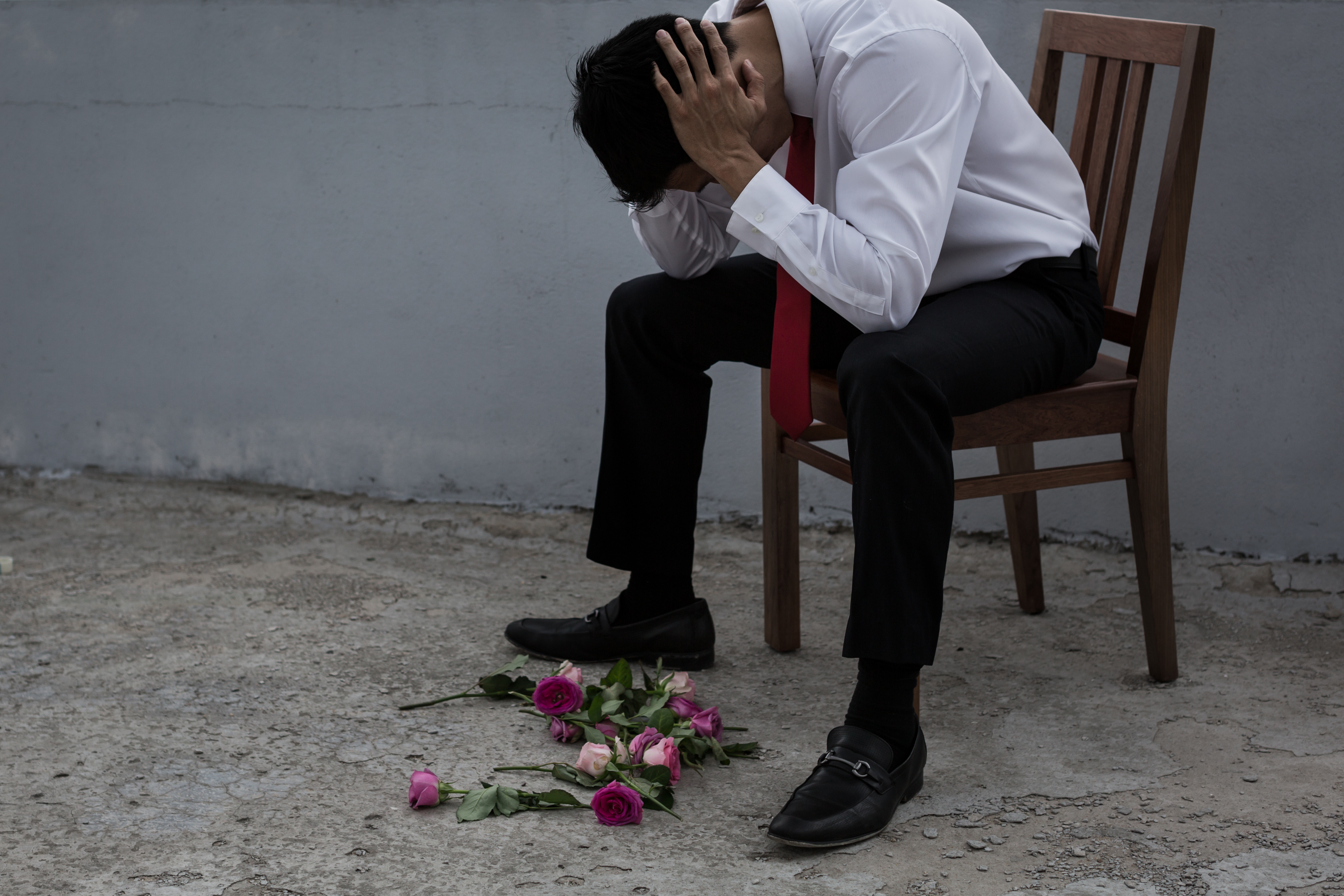 A man looking sad with flowers scattered on the ground | Source: Shutterstock