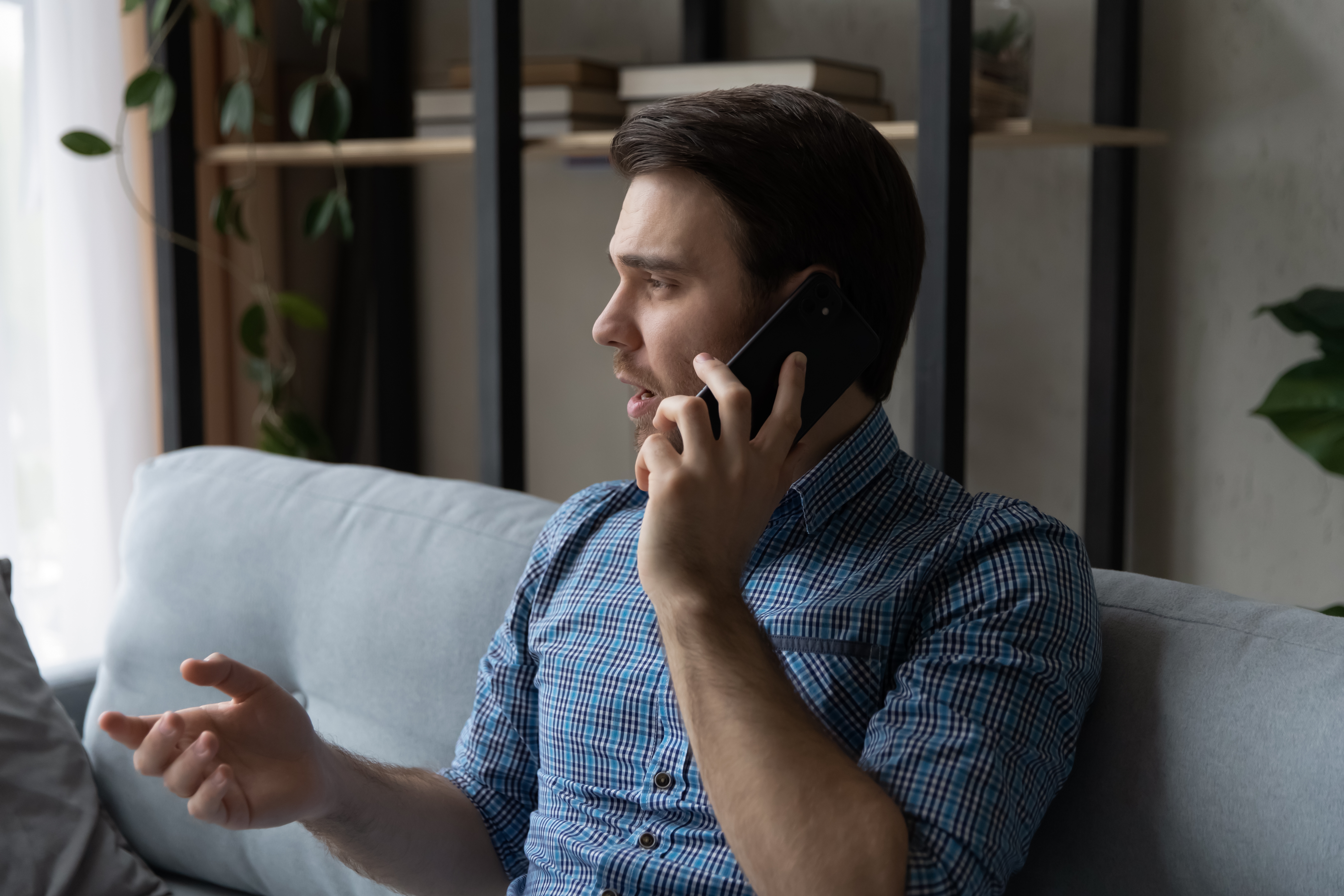 Serious thoughtful mobile phone user making telephone call from home, speaking on cell. | Source: Shutterstock