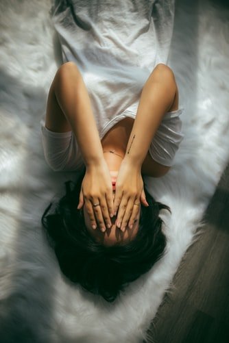 Une femme allongée sur un lit avec la main sur le visage. | Photo : Unsplash Une femme allongée sur un lit avec la main sur le visage. | Photo : Unsplash