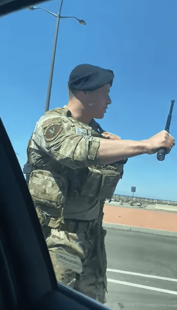 Guard standing in front of a car window while holding a baton. │ Source: facebook.com/delilah.chacon.3