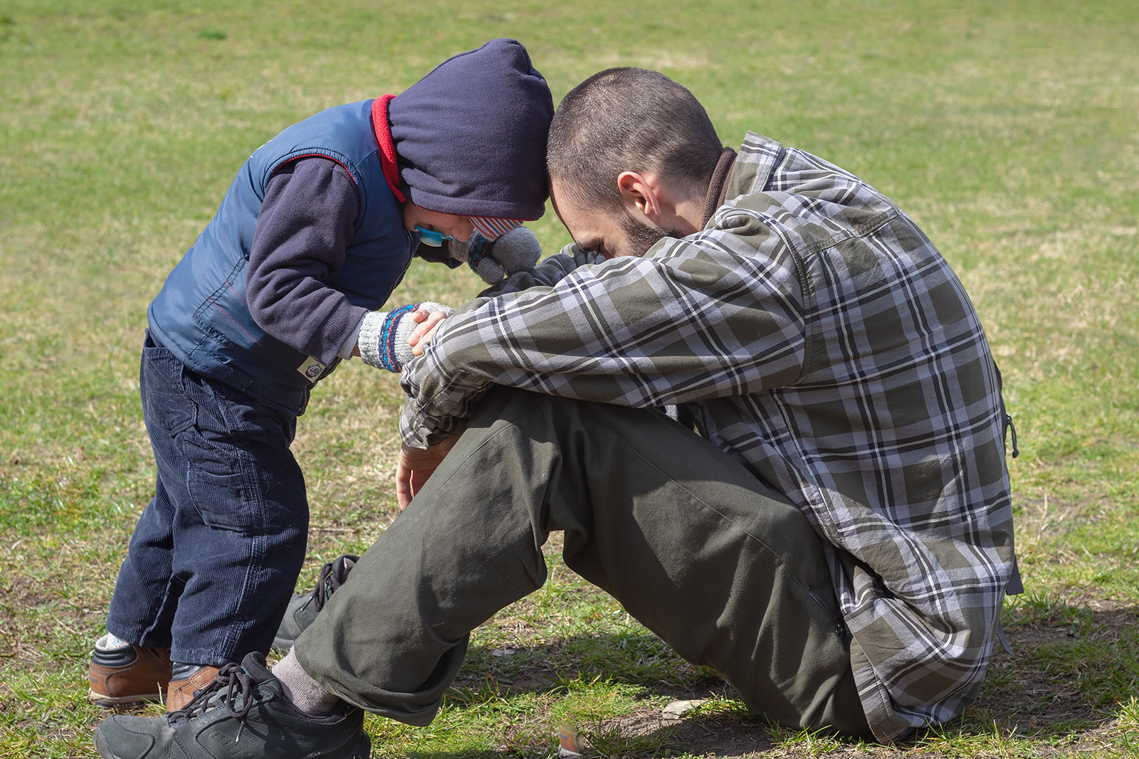 A father and son sitting on a grassy field | Source: Flickr