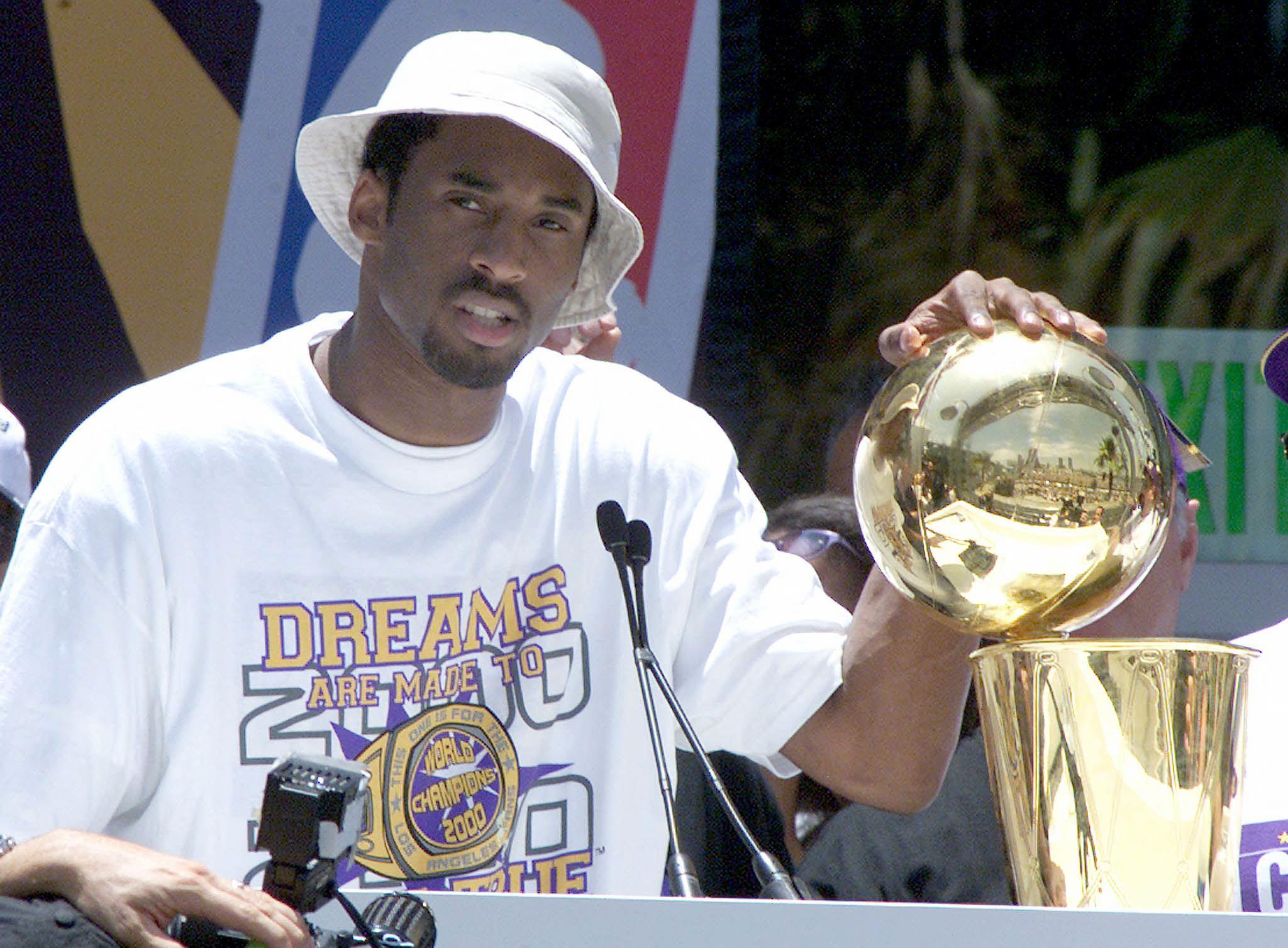 Kobe Bryant puts his hand on the NBA championship trophy at the end of the Los Angeles Lakers' victory parade through downtown Los Angeles on June 21, 2000. | Source: Getty Images