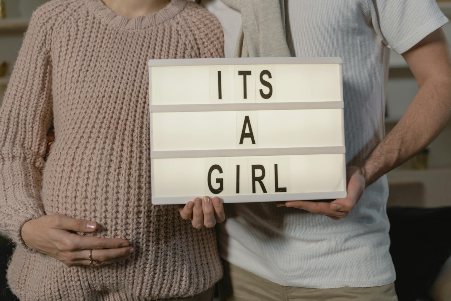 A pregnant couple holding a letter board | Source: Pexels