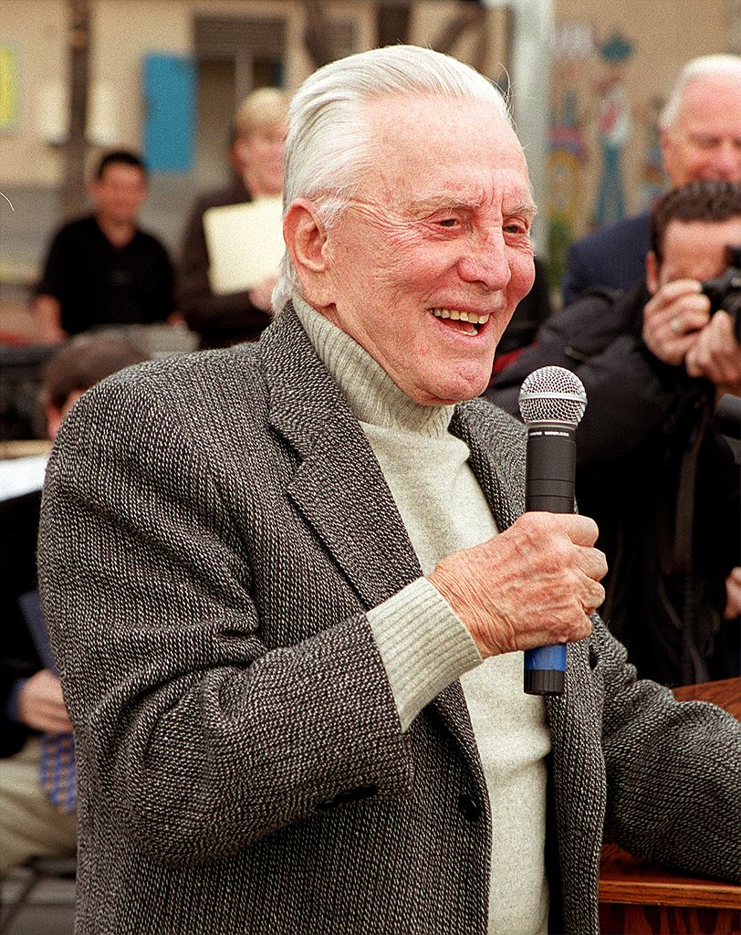 Kirk Douglas talks to students during the opening of the 100th playground that he has made possible through his donations | Photo: Getty Images