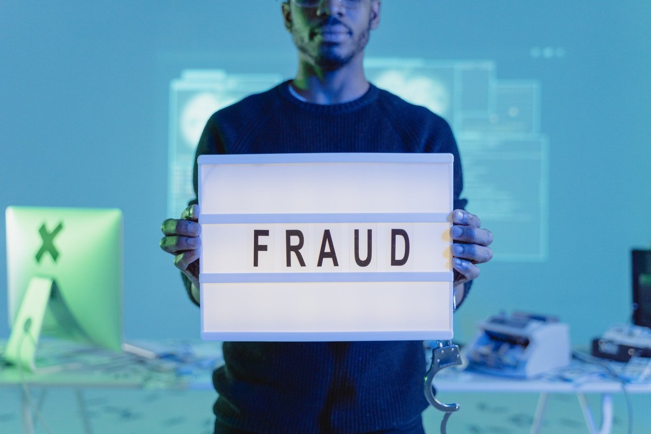 A man holding a board with fraud written on it | Photo: Pexels