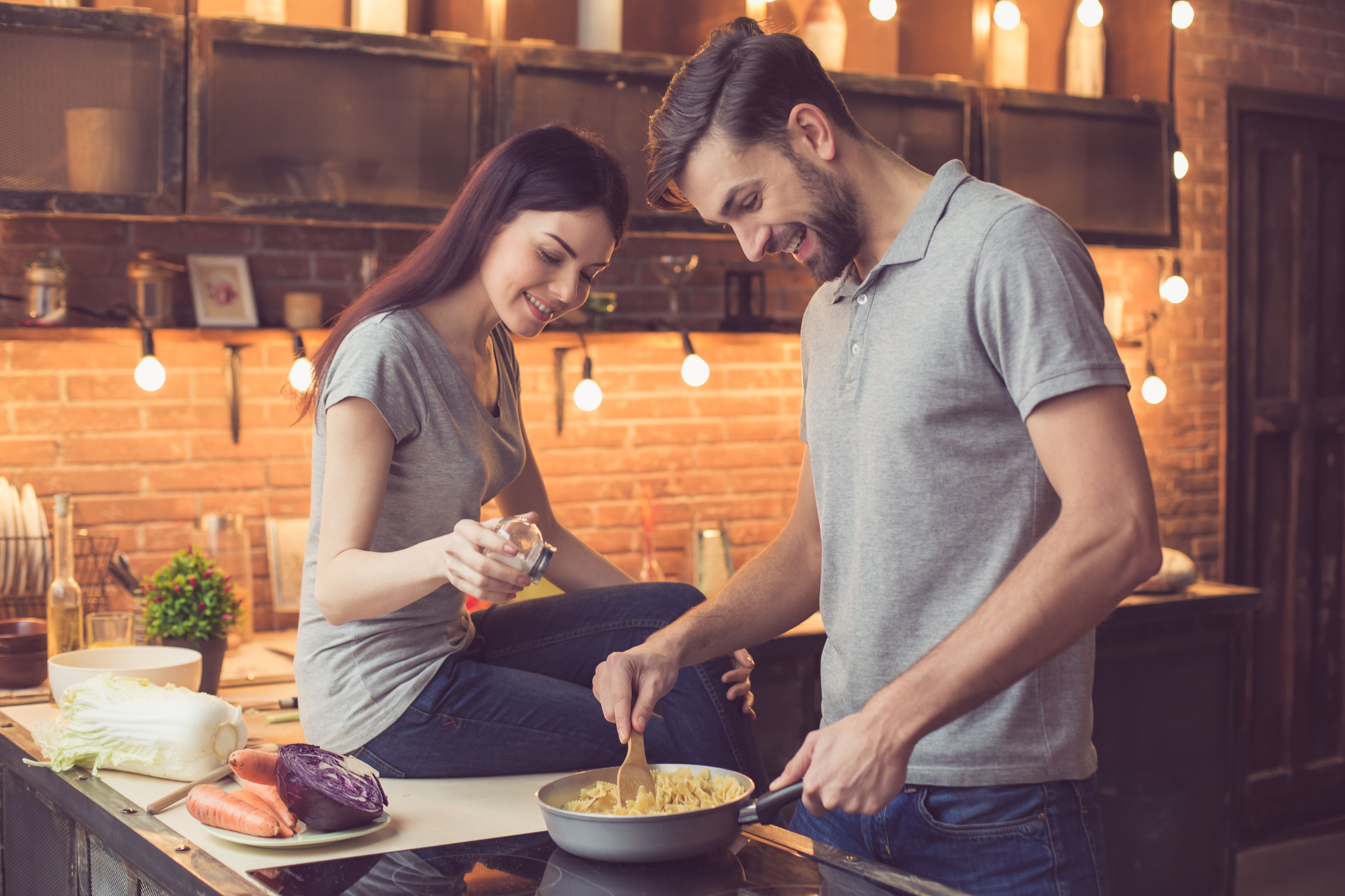 A couple cooking and talking in the kitchen. | Source: Shutterstock