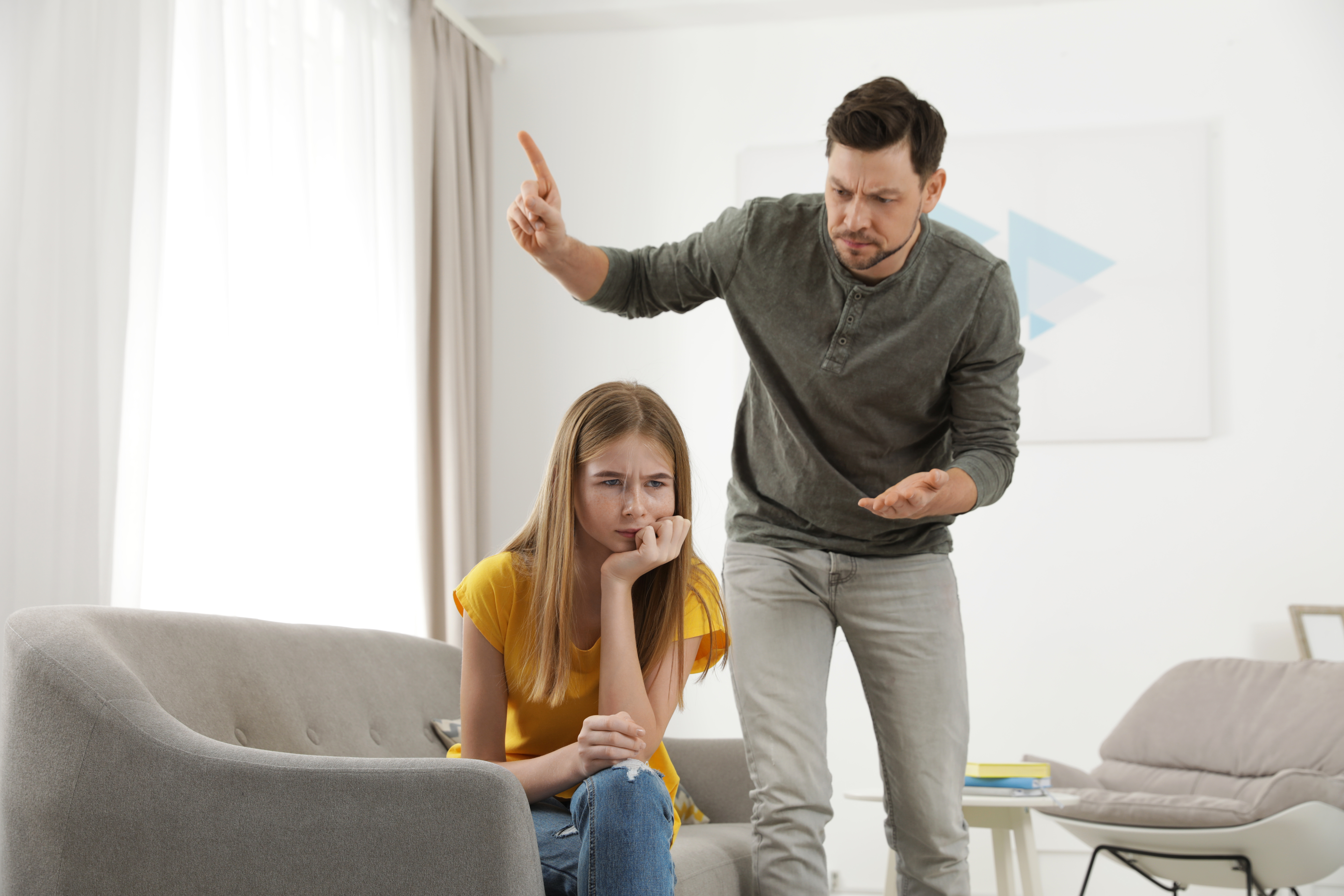 A man scolding a girl inside a living room | Source: Shutterstock