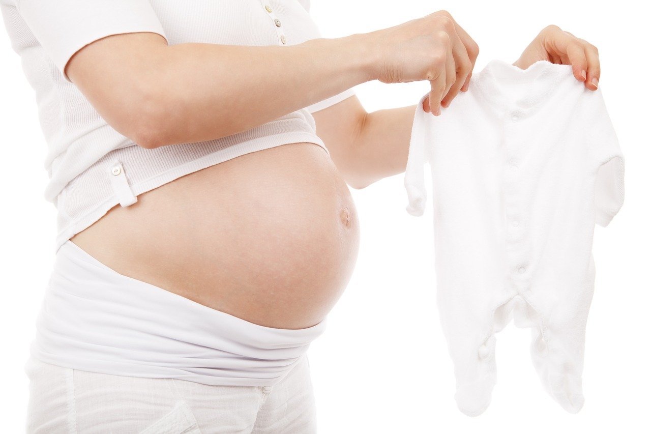 Embarazada sosteniendo una ropa de bebé. | Foto: Pixabay
