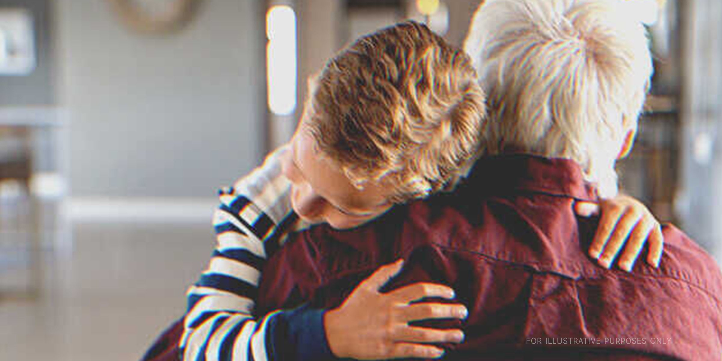 A young boy hugging his grandfather | Source: Shutterstock