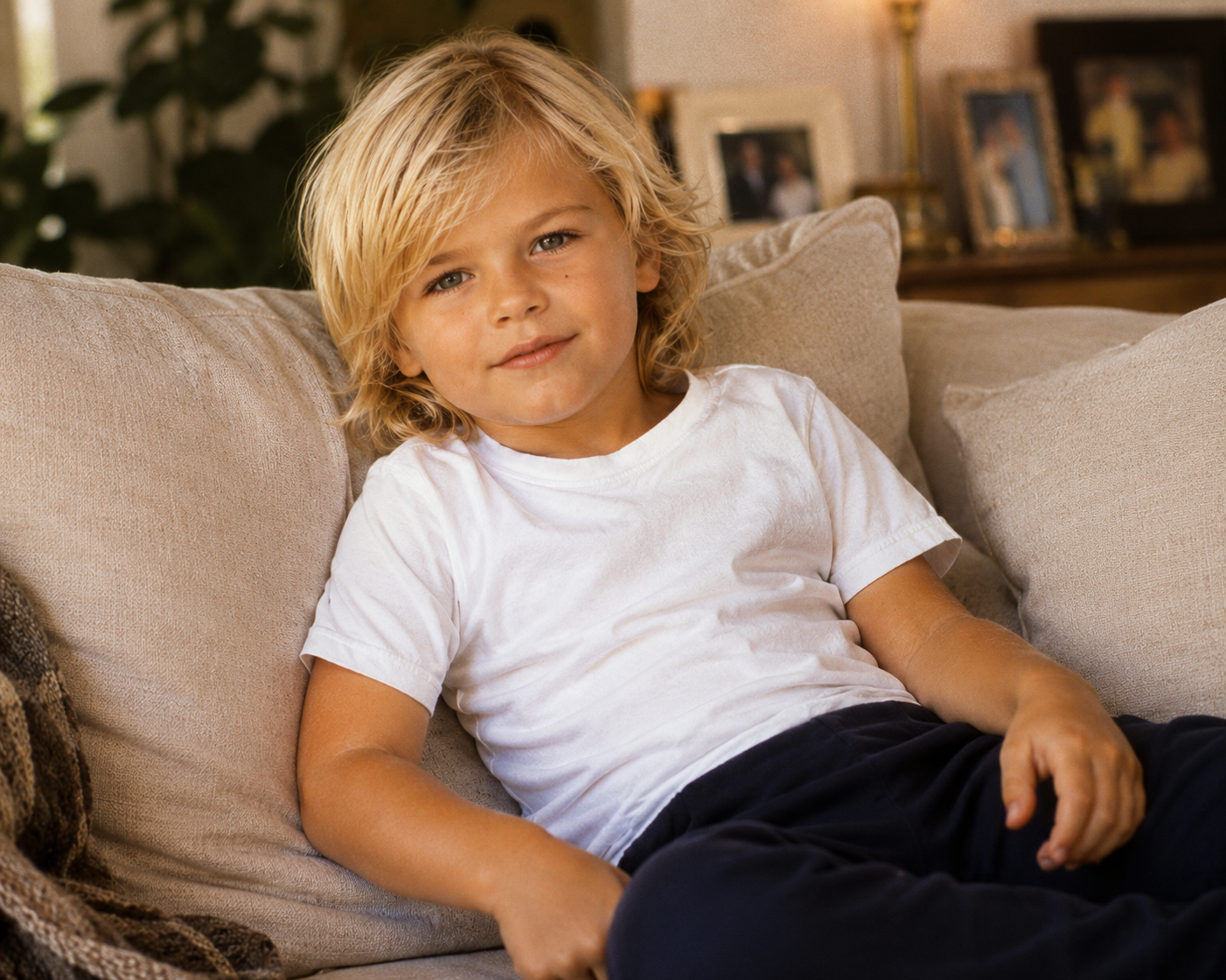 An AI-generated portrait portrays the younger imagined son relaxing on a couch in a casual white t-shirt, showcasing soft natural lighting and a cozy home aesthetic. | Source: ChatGPT