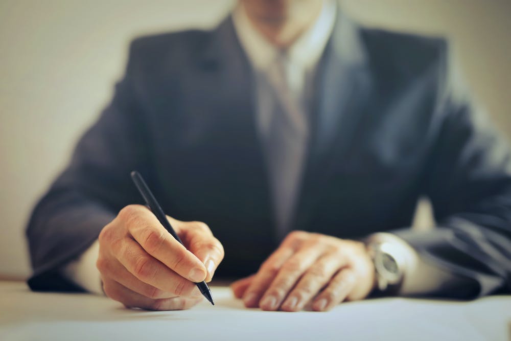 Hombre firmando un documento en una oficina. | Foto: Pexels