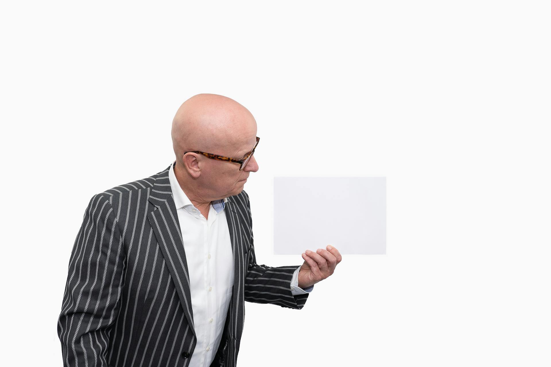 A senior man holding a sheet of paper | Source: Pexels
