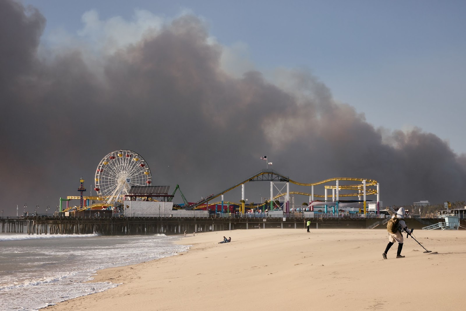 A photo of Santa Monica Pier with the Palisades fire burning in the distance on January 7, 2025. | Source: Getty Images