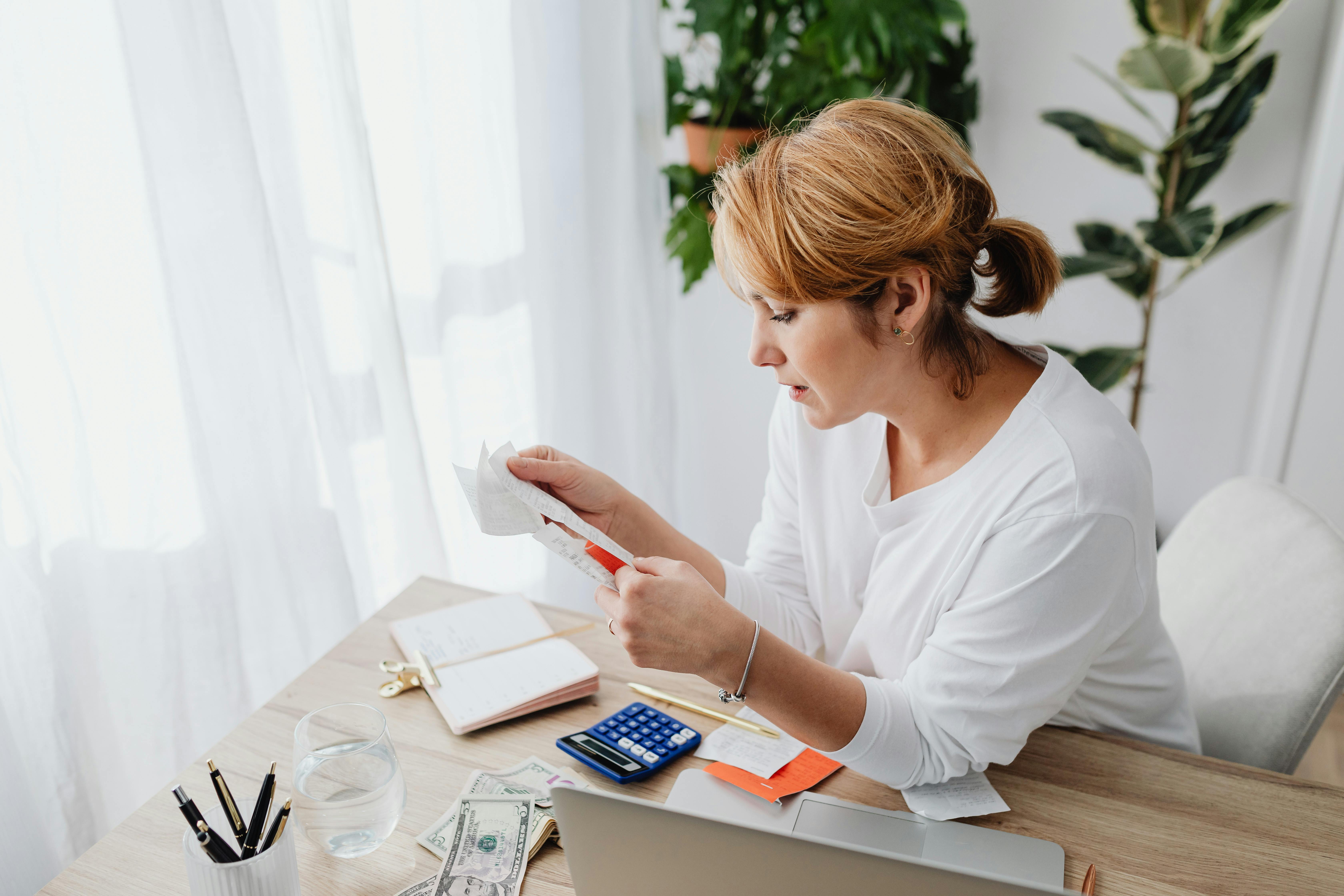 Una mujer mirando un trozo de papel sobre un escritorio | Fuente: Pexels