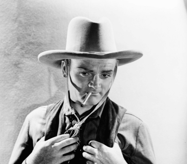 Portrait of actor James Cagney dressed up in a cowboy costume and smoking a cigarette, as he appears in the movie "Oklahoma Kid," with Warner Brothers Studios, 1939 | Photo: Getty Images