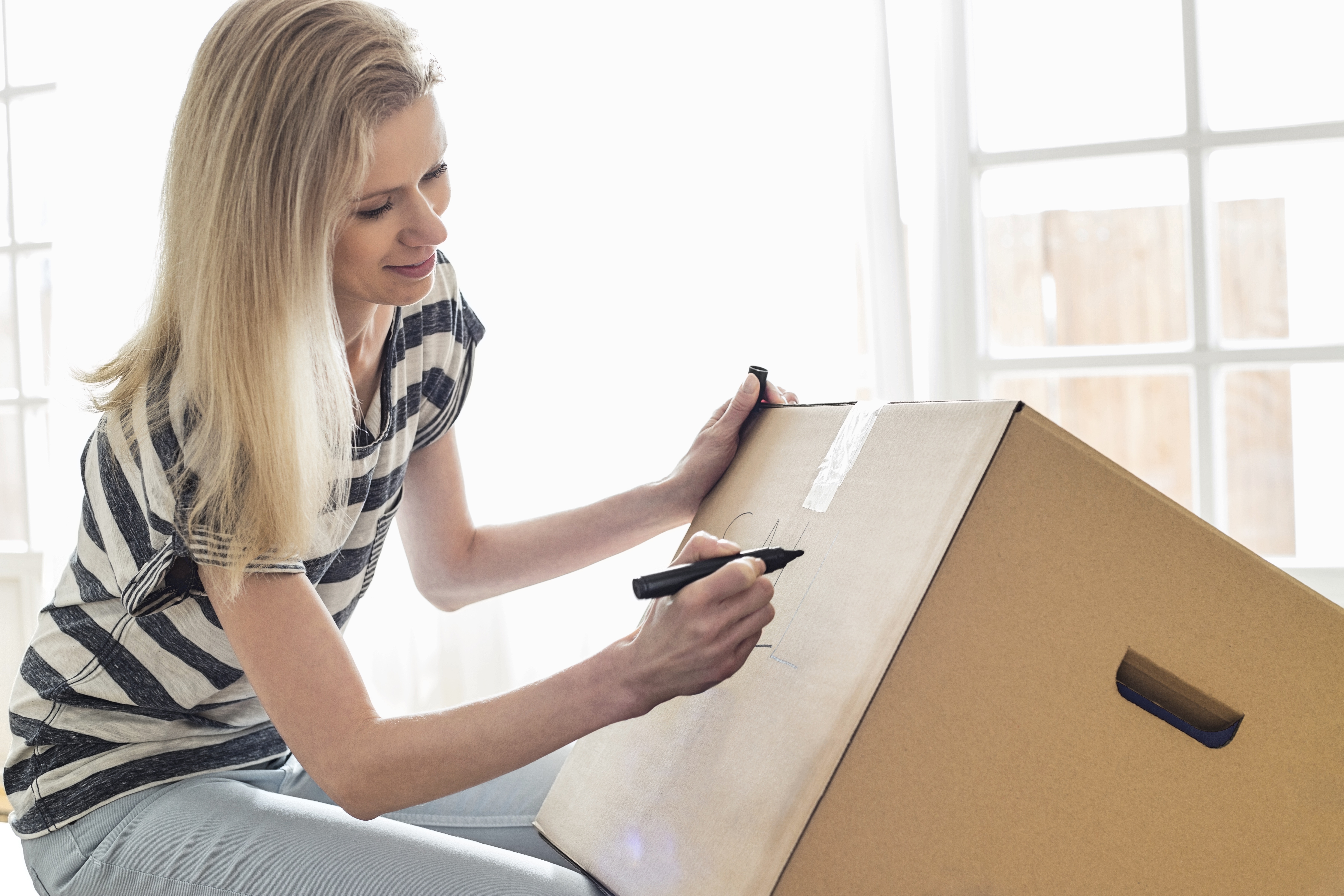 A woman labelling a box | Source: Shutterstock