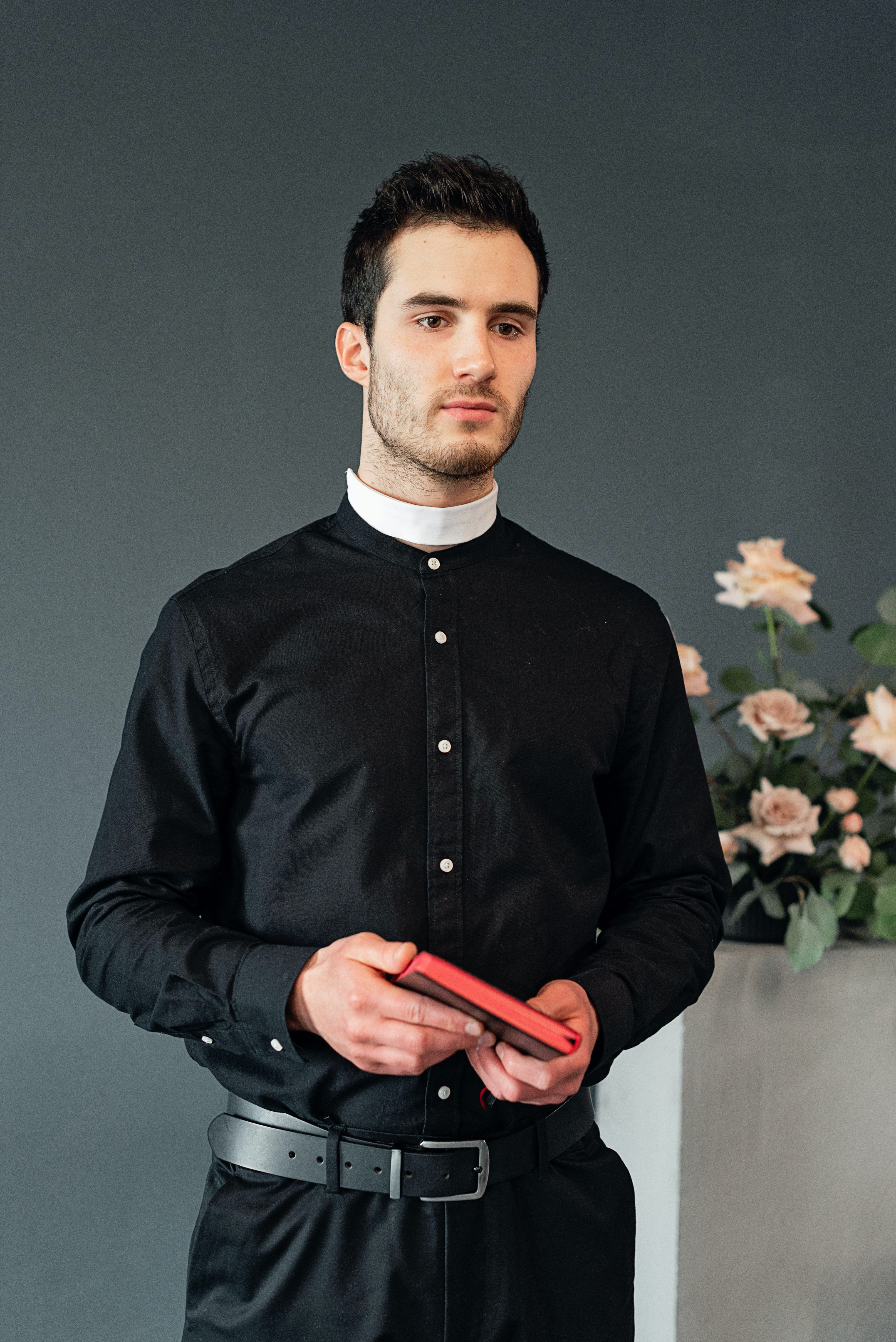 A priest standing with a Bible in his hands. | Photo: Pexels/ Mikhail Nilov