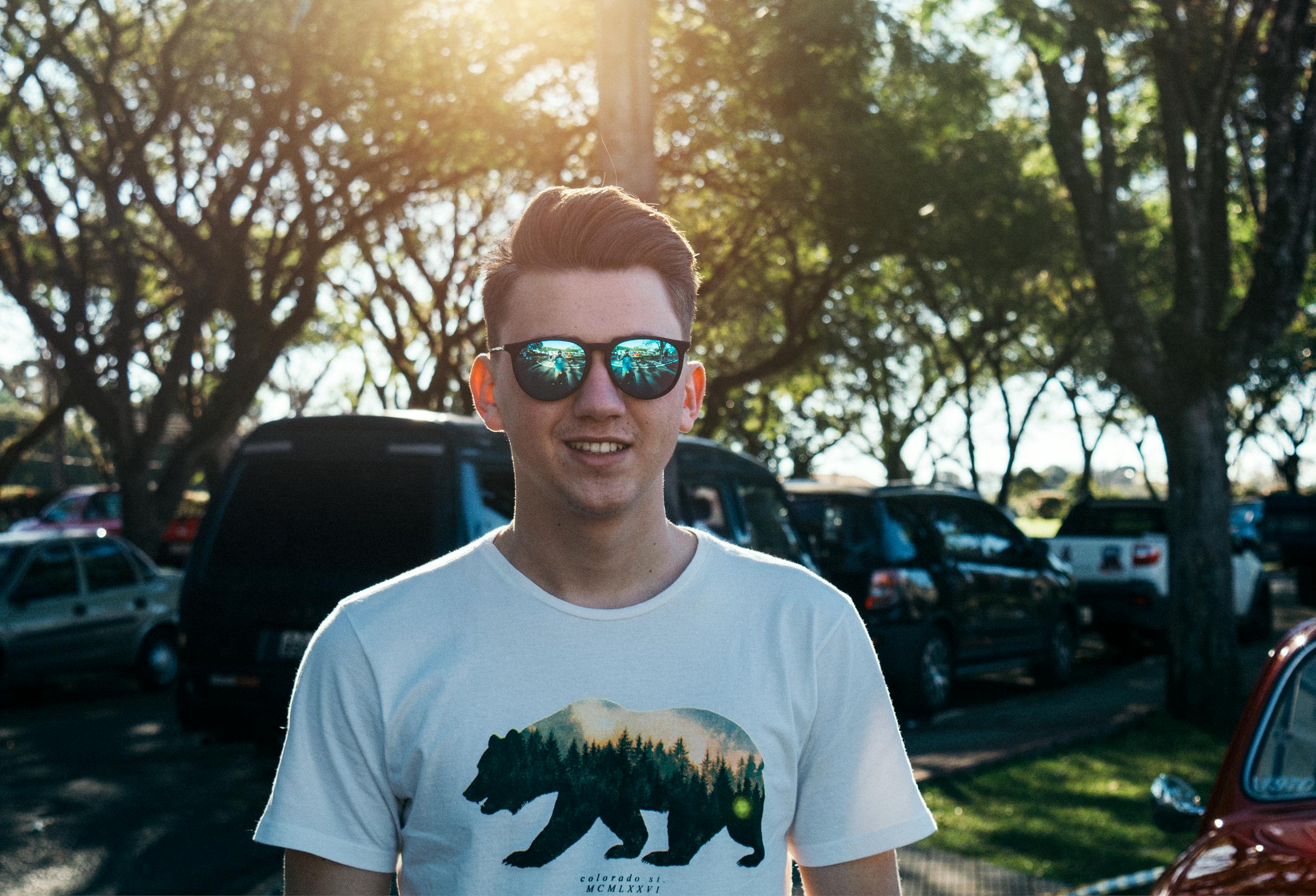 A man in sunglasses out in front of some parked cars | Source: Pexels