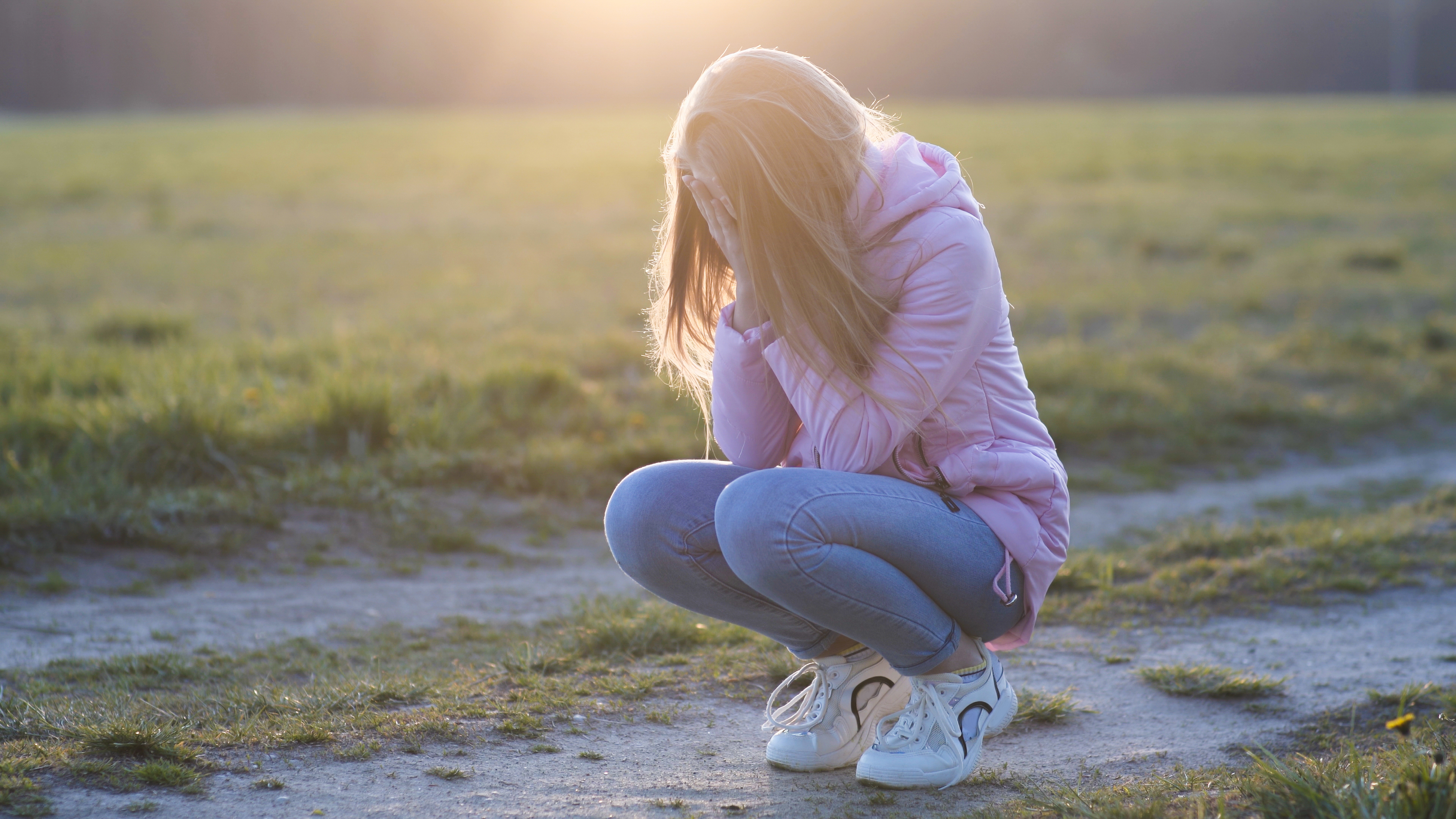 A young girl cries while sitting alone outside | Source: Shutterstock