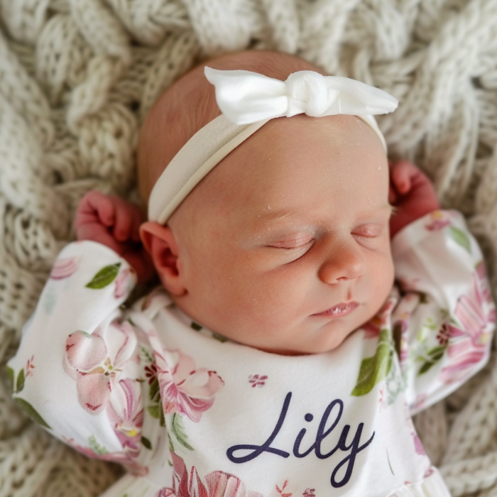A newborn baby girl wearing a shirt with "Lily" written on it | Source: Midjourney