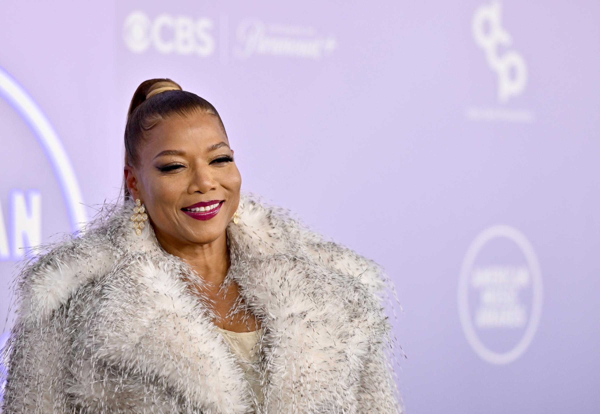 Queen Latifah turned heads in a textured silver coat with oversized sleeves, a sleek ponytail, and sparkling earrings that stood out against the purple AMA backdrop | Source: Getty Images