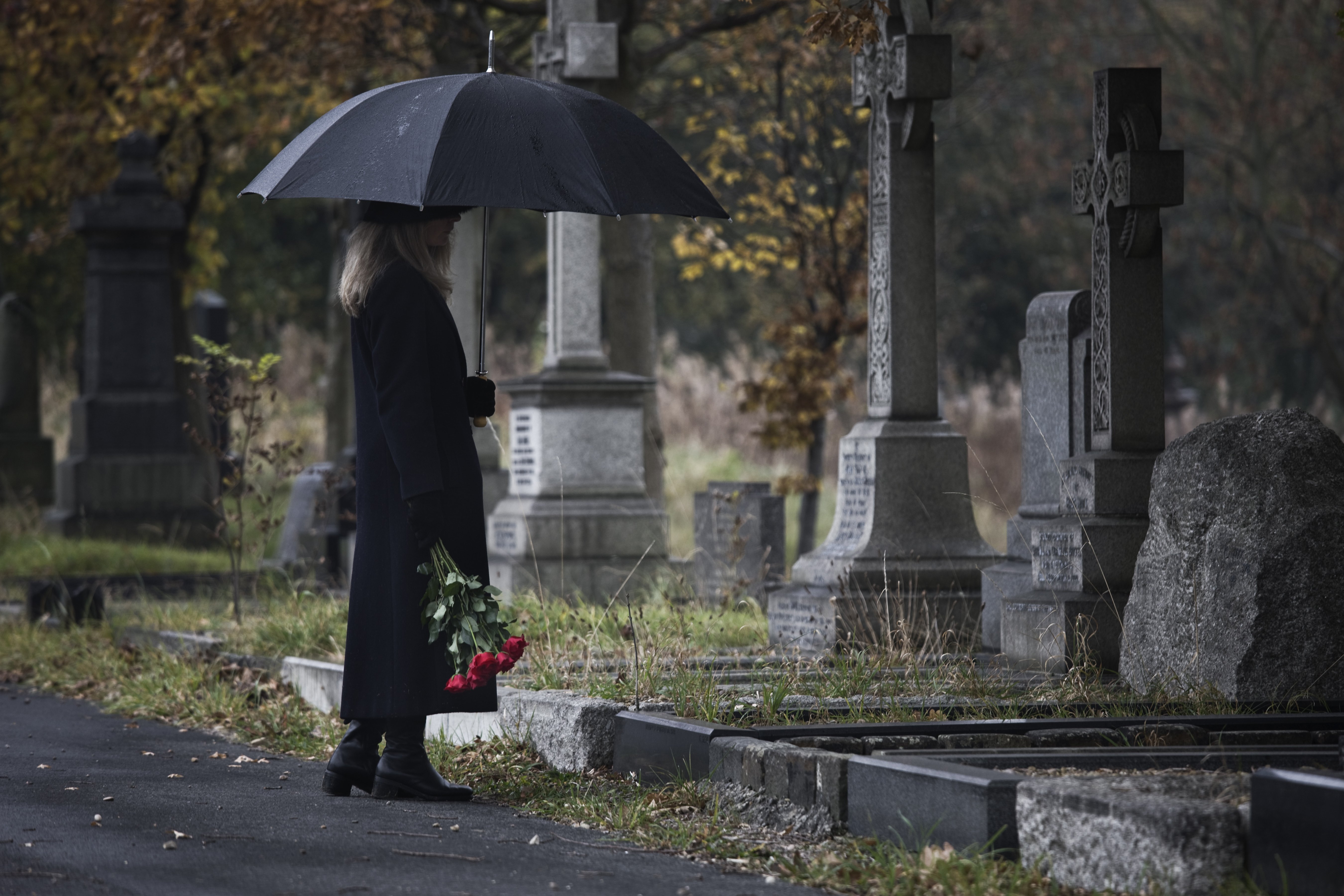 Mujer vestida de negro frente a unas tumbas en un cementerio. | Foto: Getty Images