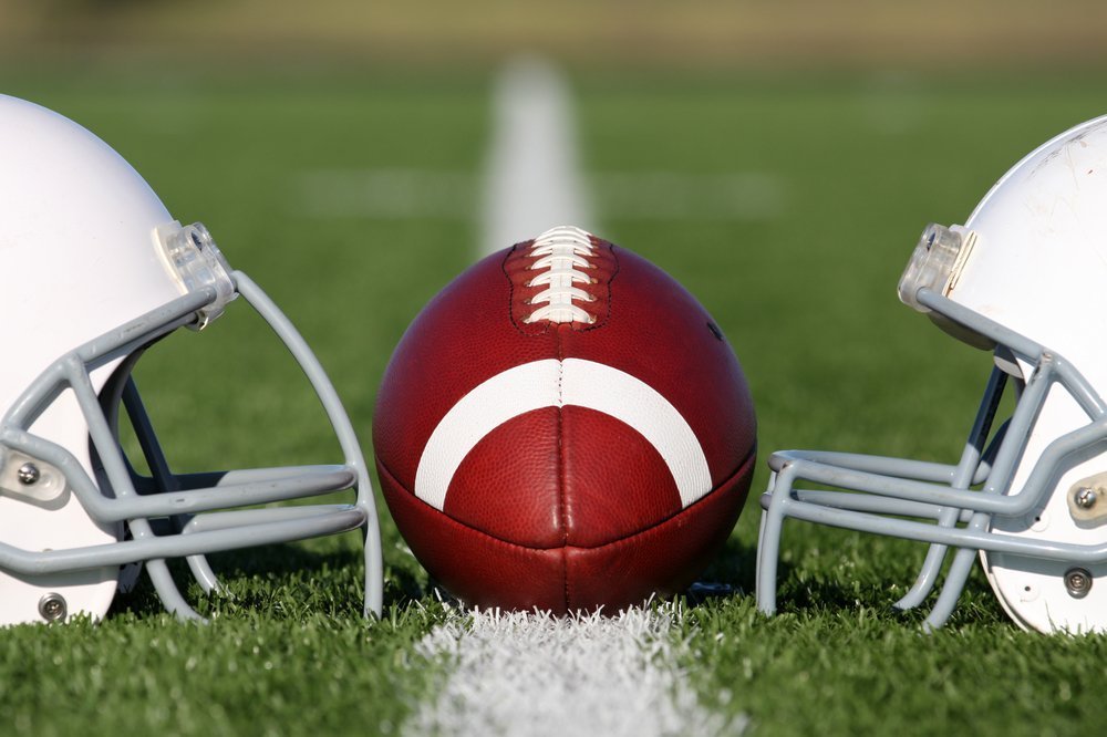 American Football and Helmets on the field. | Photo: Shutterstock