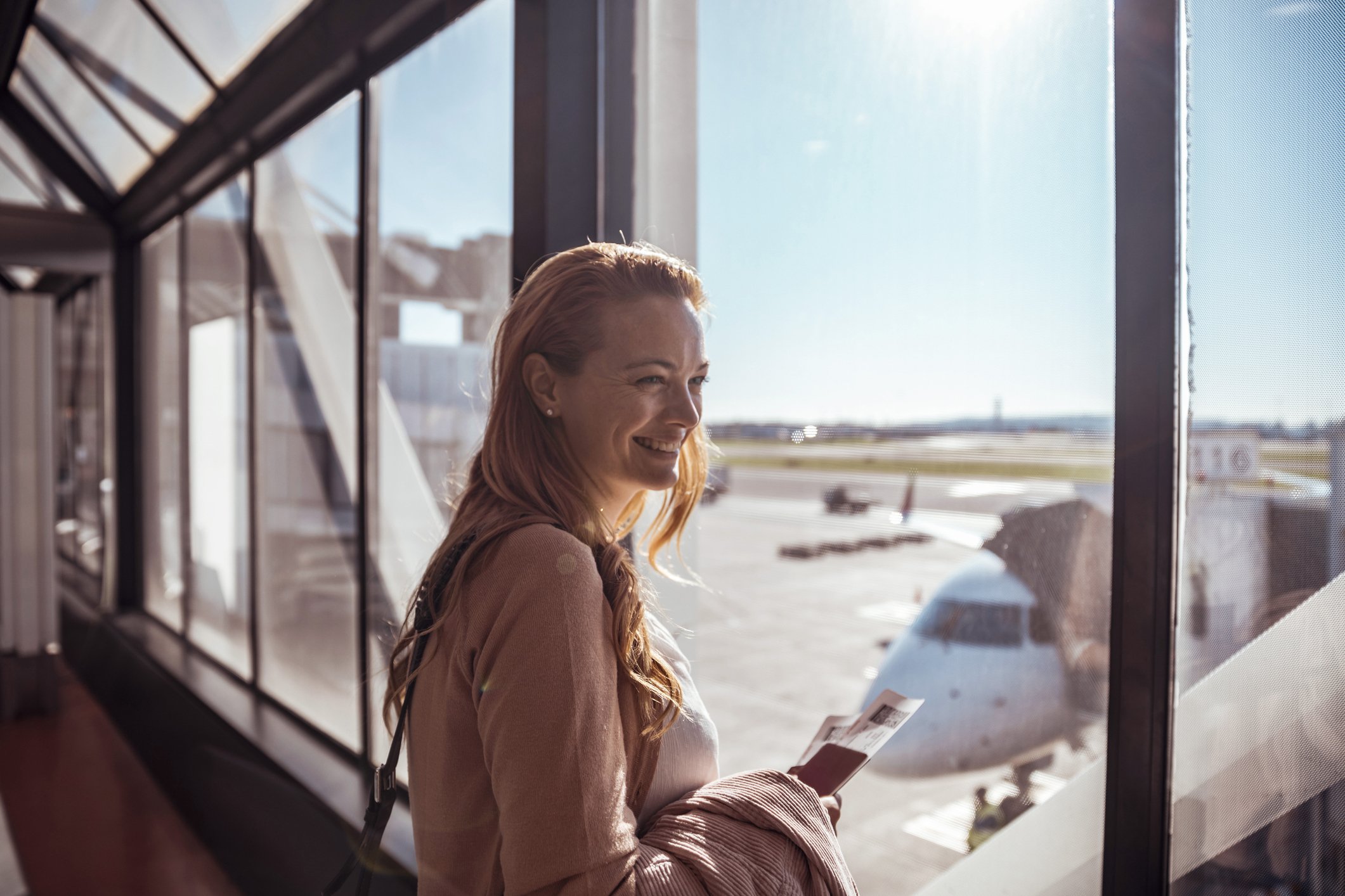 A picture of a woman smiling and waiting to board the plane. | Photo: Getty Images