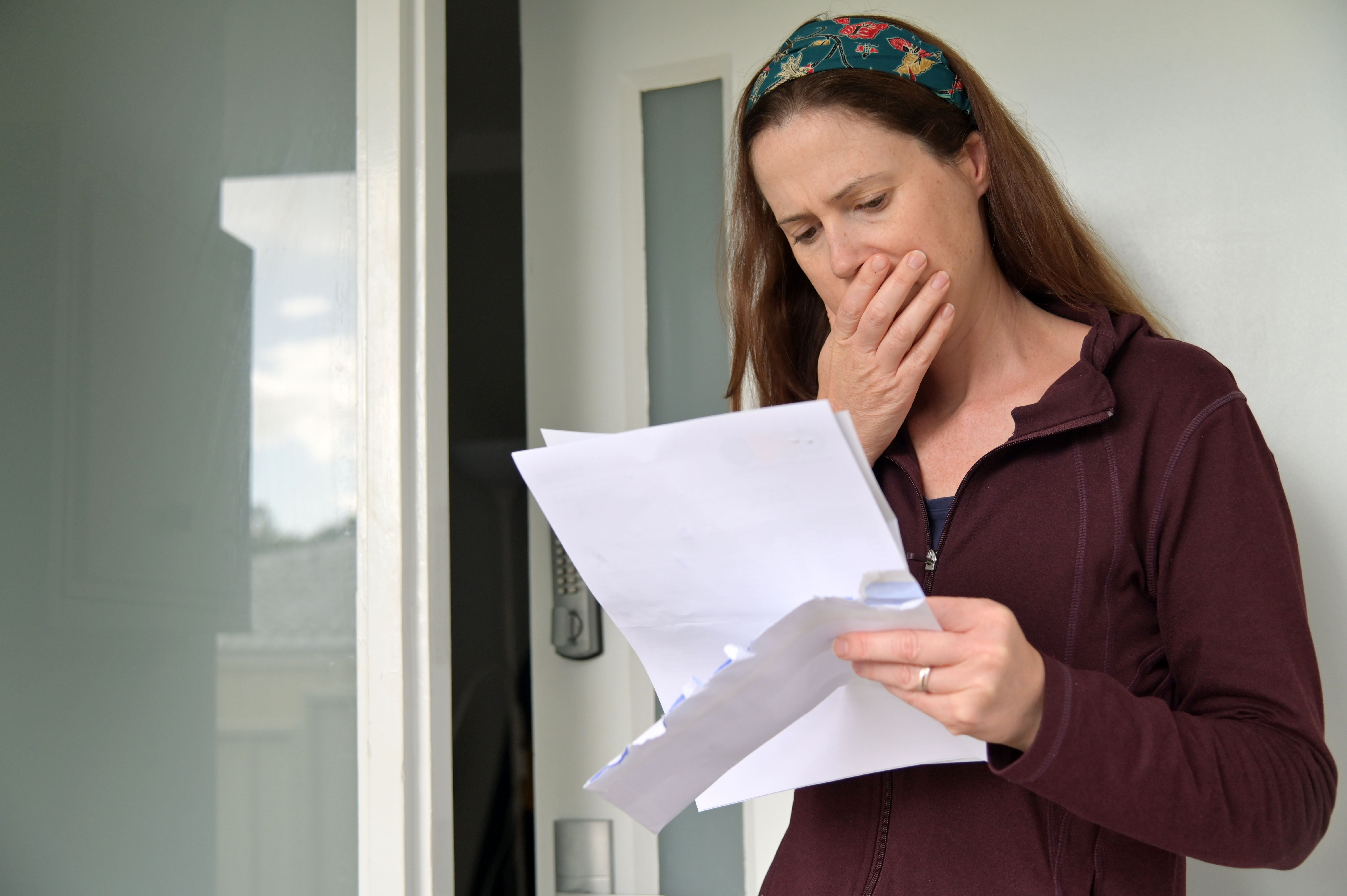 A woman holding documents with one hand on her mouth | Source: Shutterstock