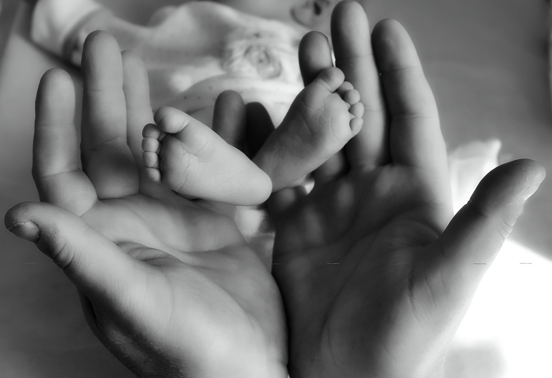 An adult holding a newborn baby's feet. | Source: Pixabay.