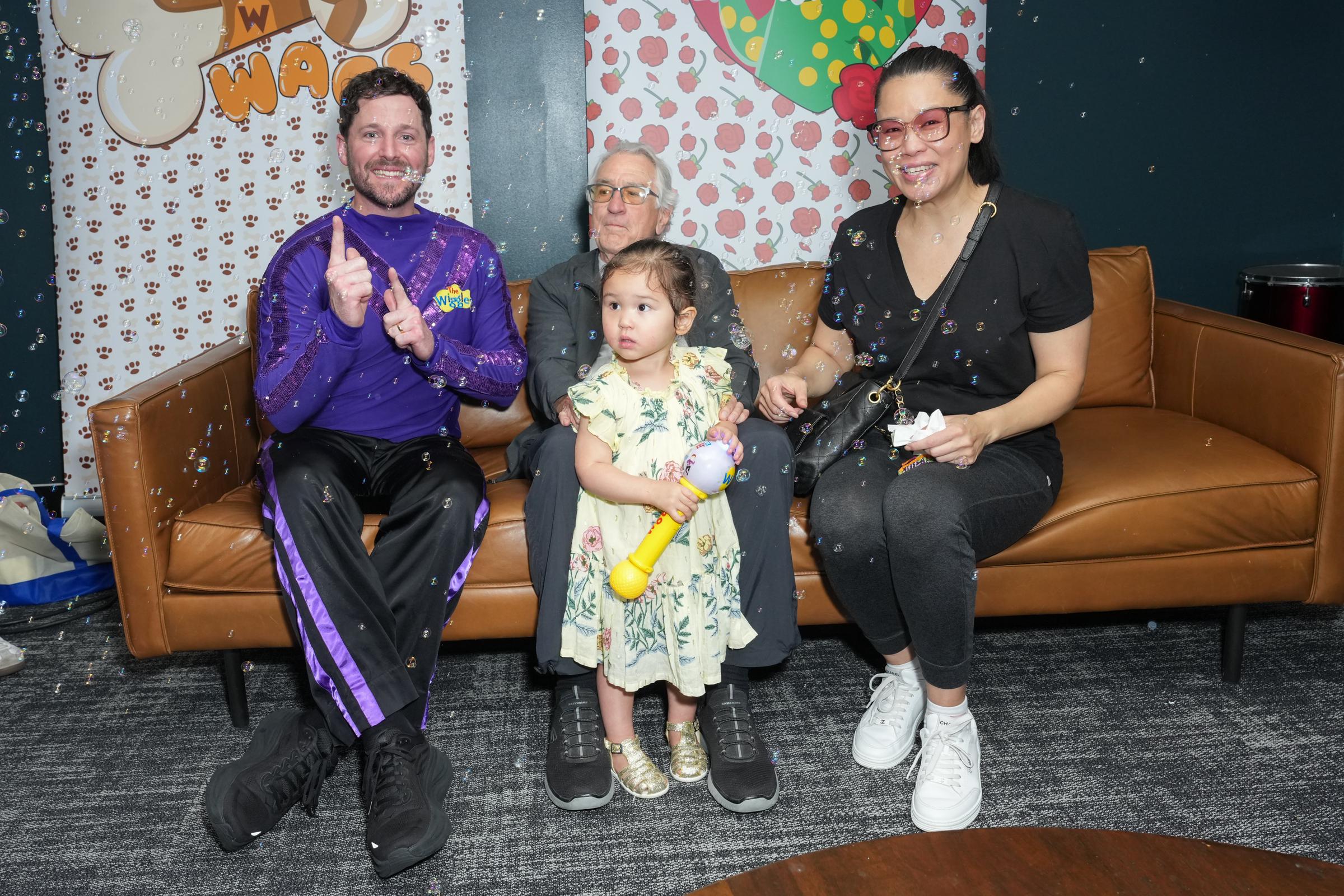 Robert De Niro, Tiffany Chen, and Gia Virginia Chen-De Niro sitting next to Lachlan Gillespie from The Wiggles during the New York tour event | Source: Getty Images