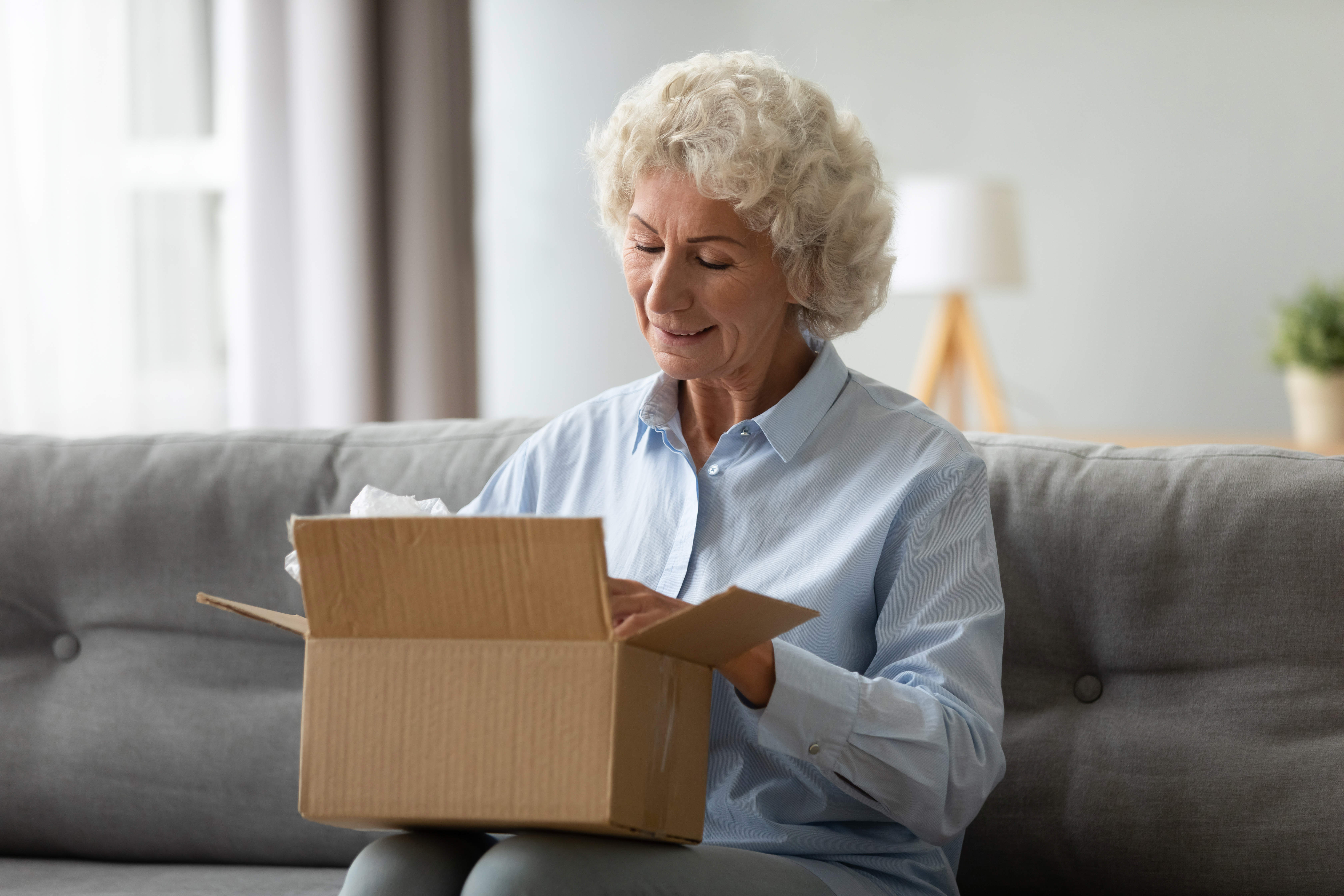 Smiling elderly woman customer receive post shipment parcel at home | Source: Getty Images