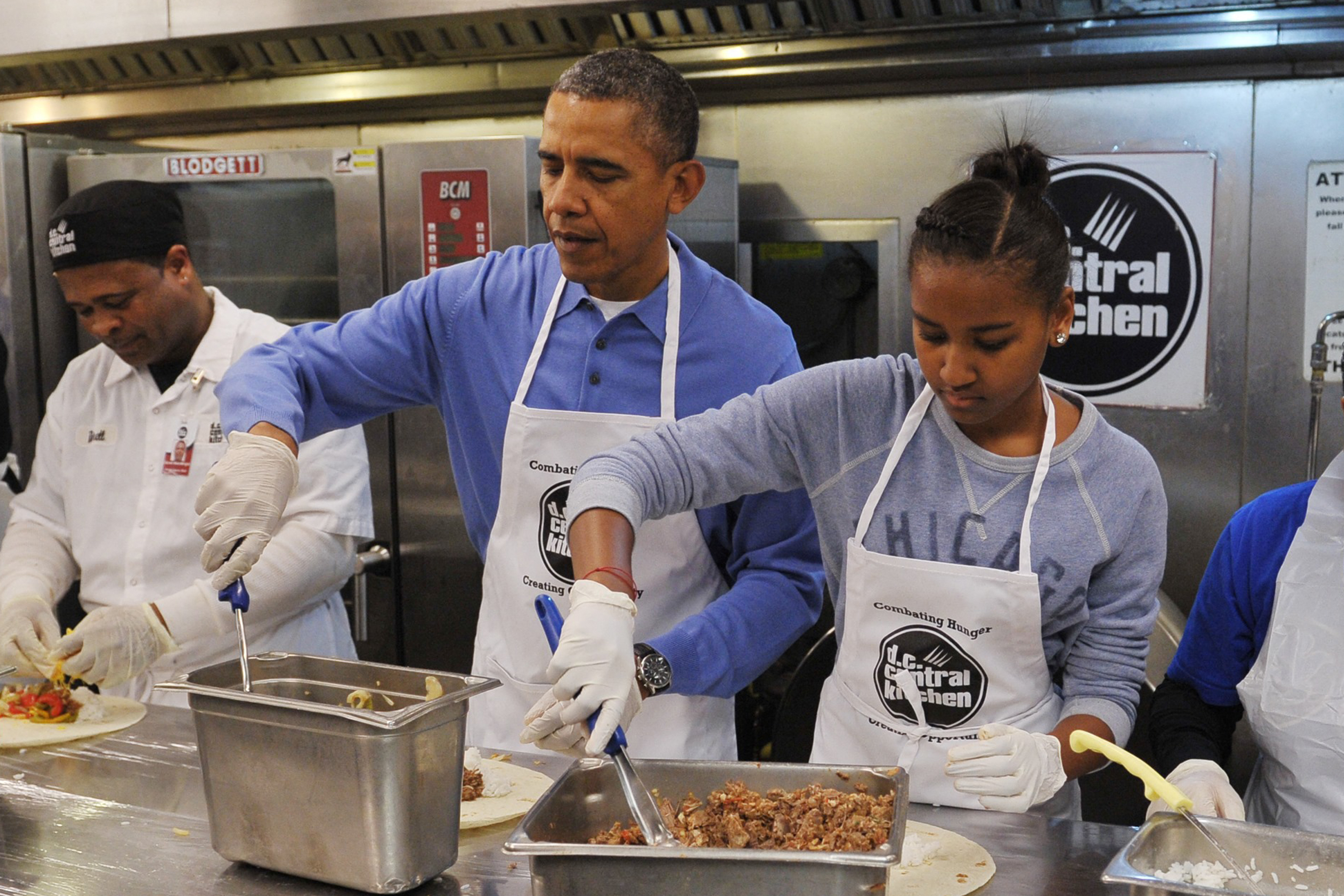 Barack and Sasha Obama taking part in a community service project, making burritos in celebration of the Martin Luther King Jr. Day in Washington, D.C. on January 20, 2014. | Source: Getty Images