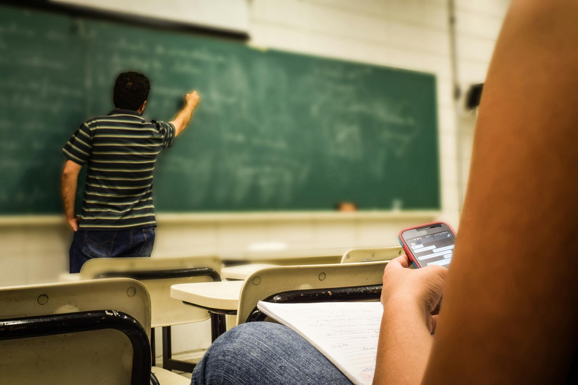 A teacher writing on a board in classroom | Source: Pexels