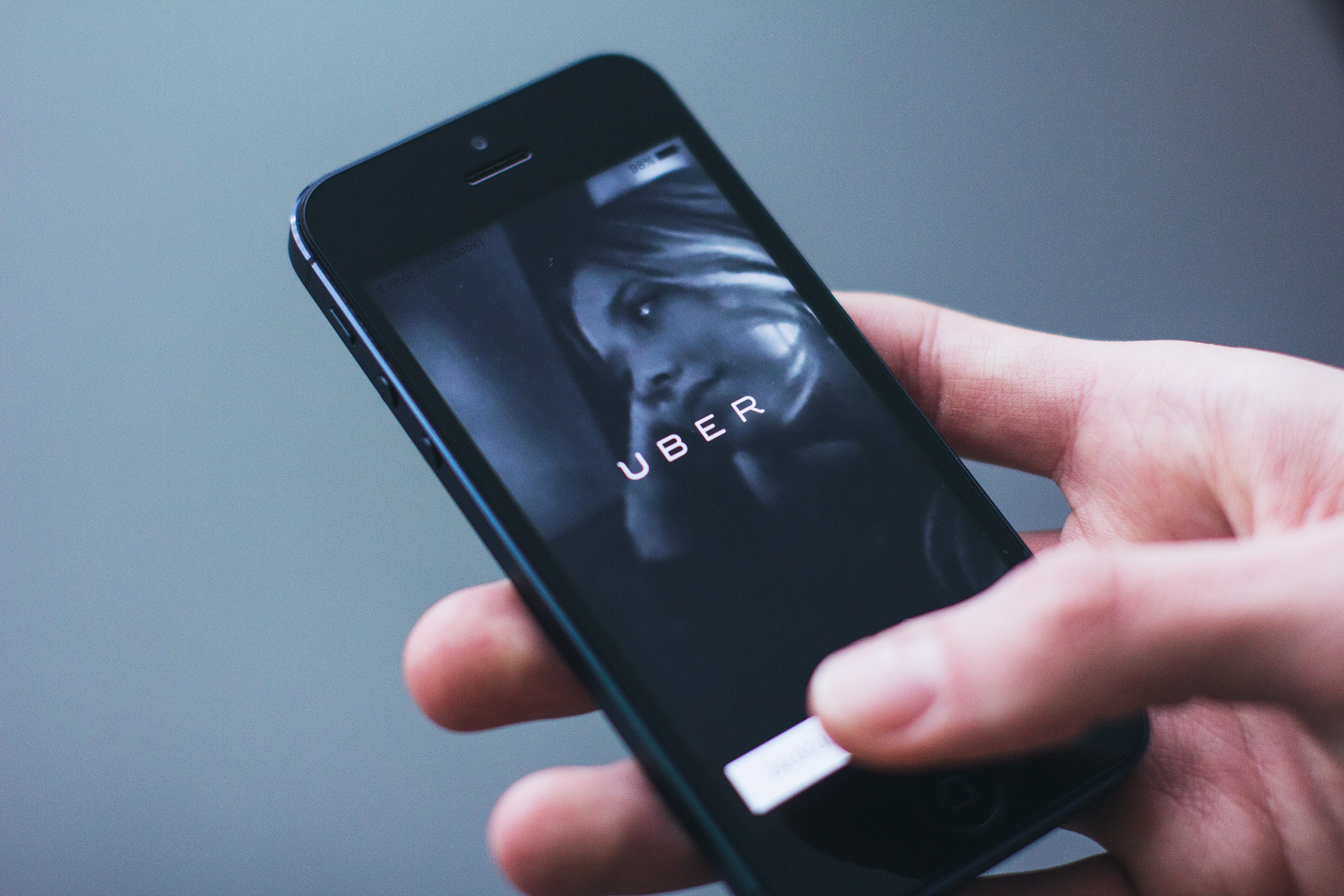 Hand holding mobile phone with Uber app. | Source: Pexels