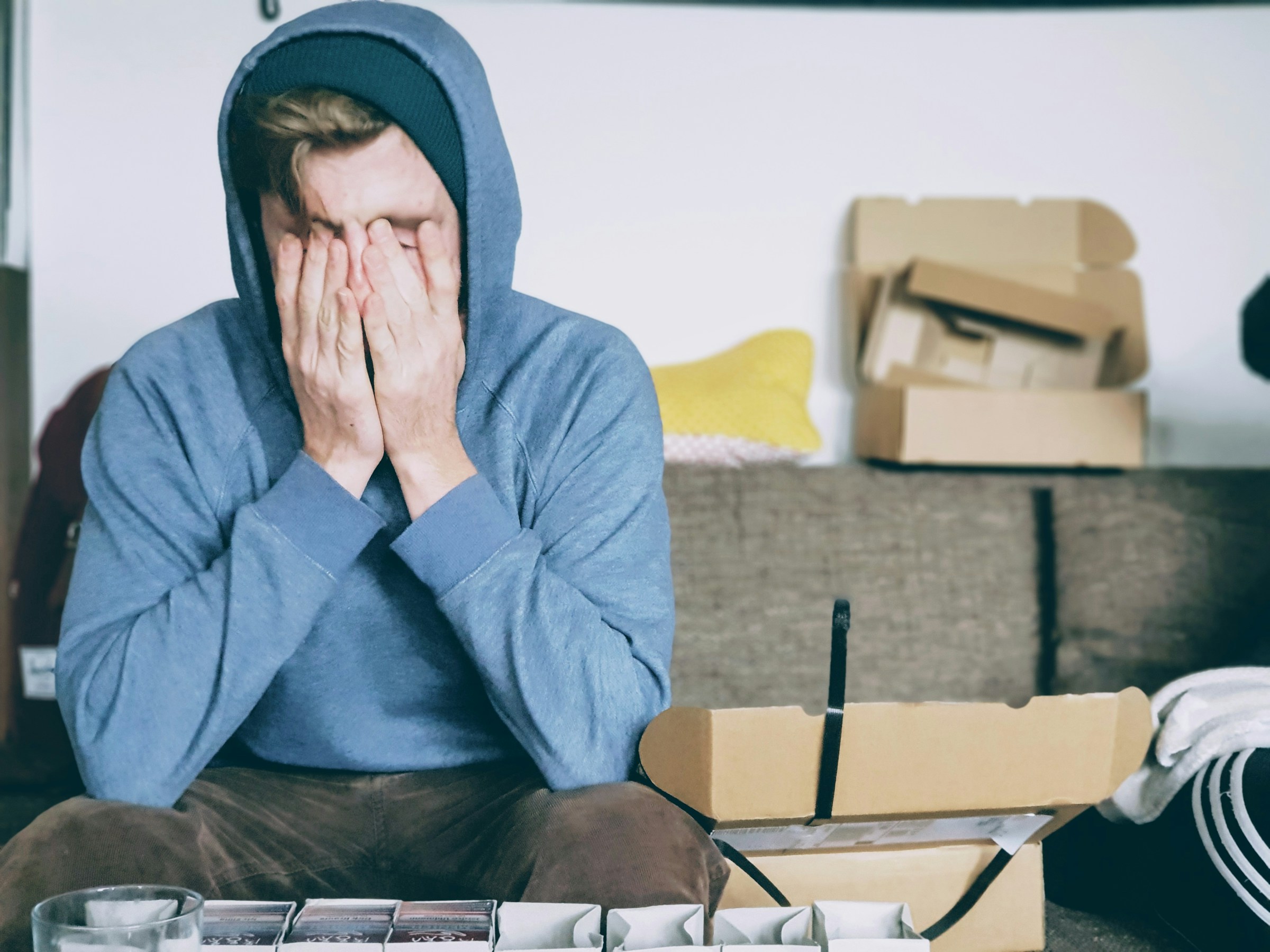 A man sitting on the couch and covering his face | Source: Unsplash